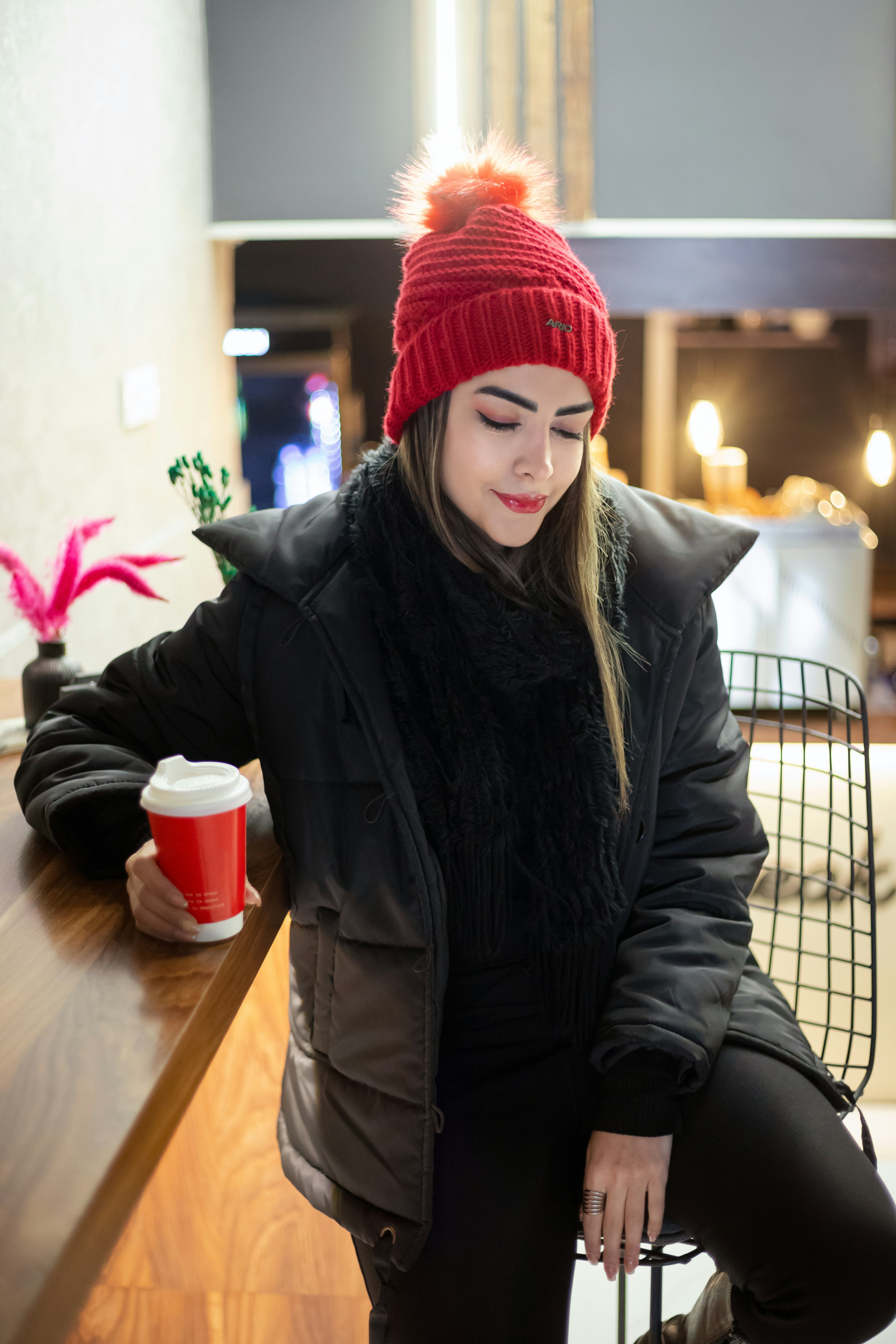 Femme en vêtements d’hiver tenant une tasse rouge.