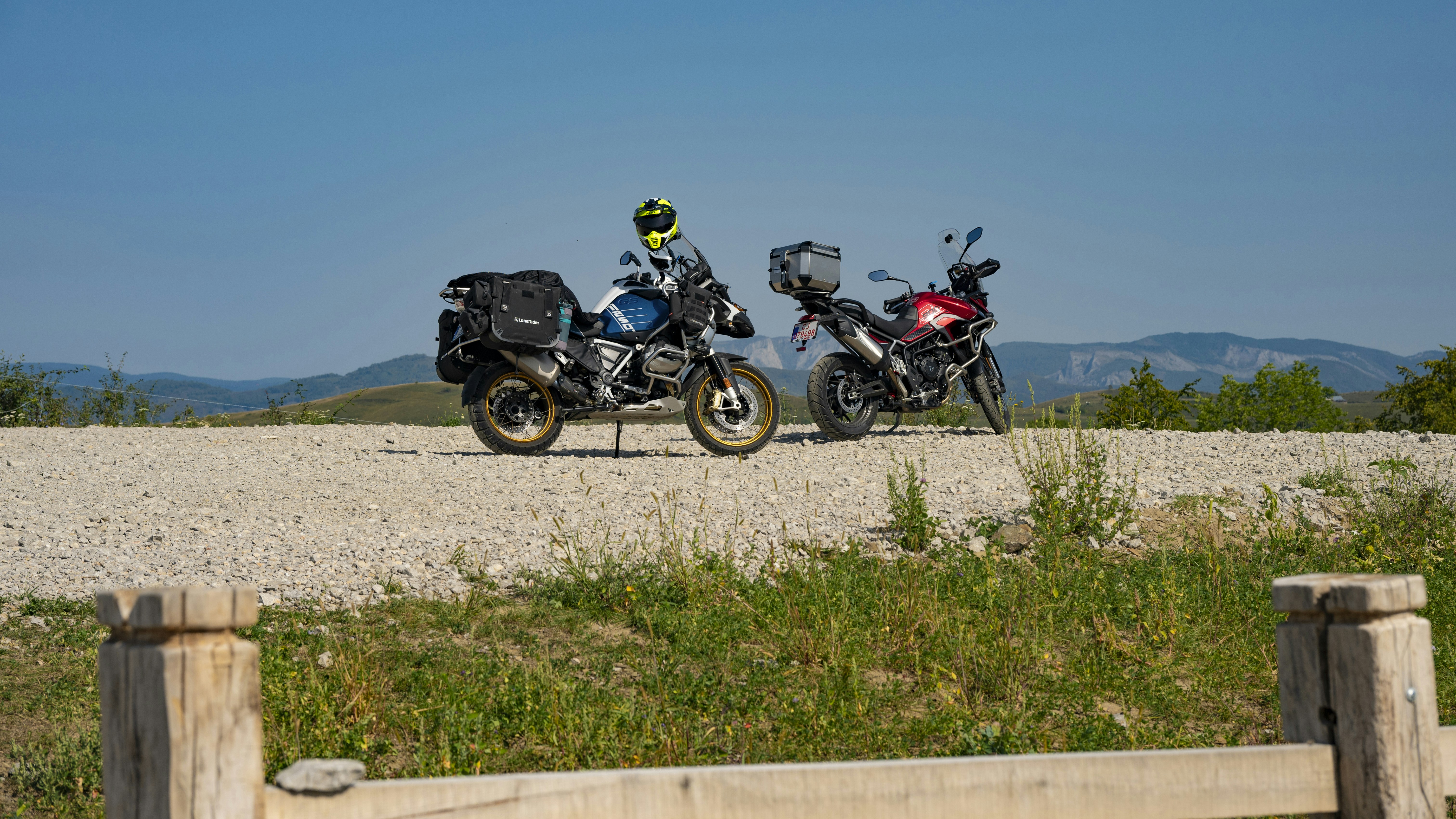 Two motorcycles parked on a dirt road with hills.