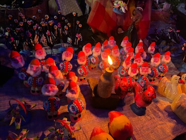 Many small gnome figurines illuminated by a single candle.