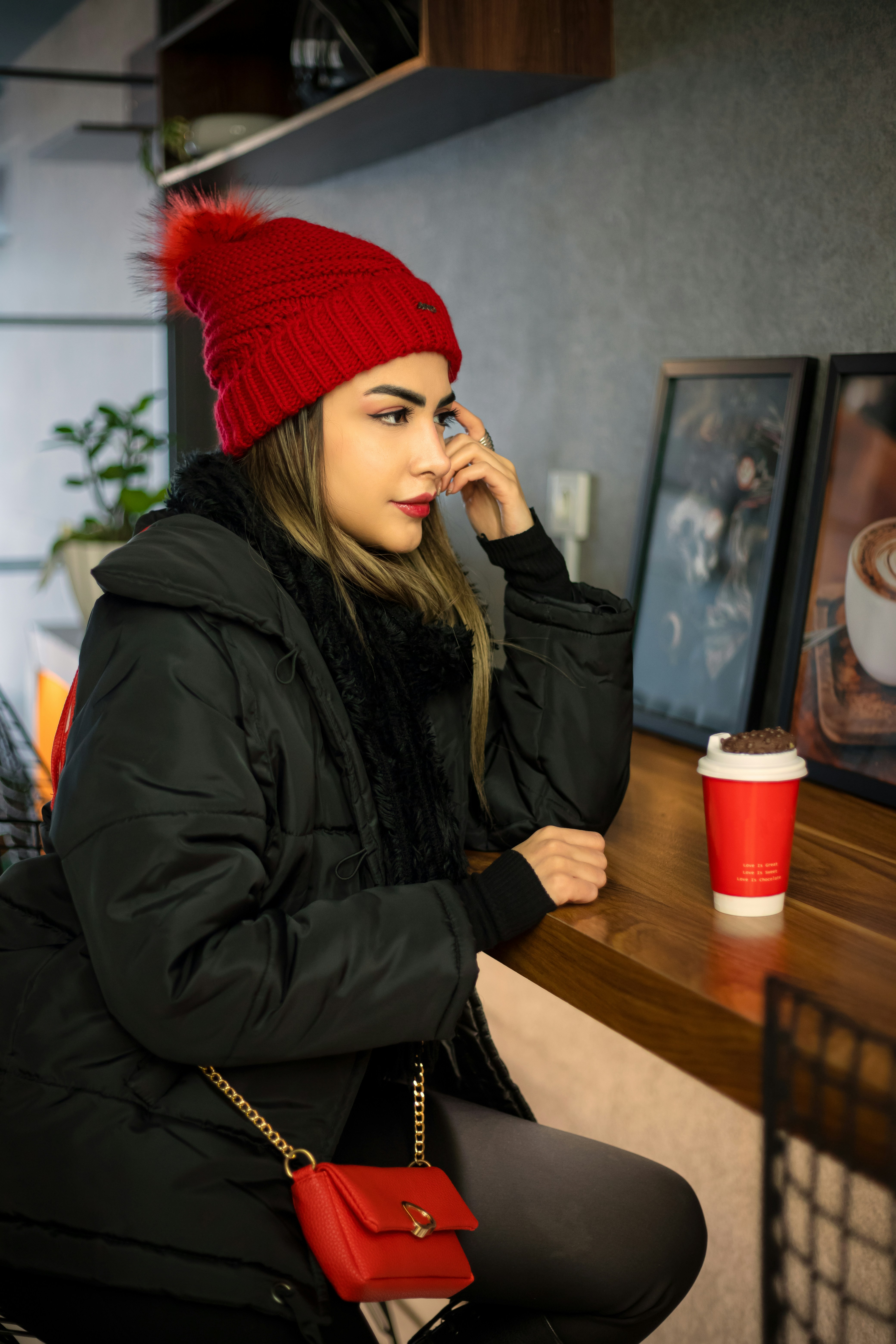 Femme au chapeau rouge et manteau noir au café
