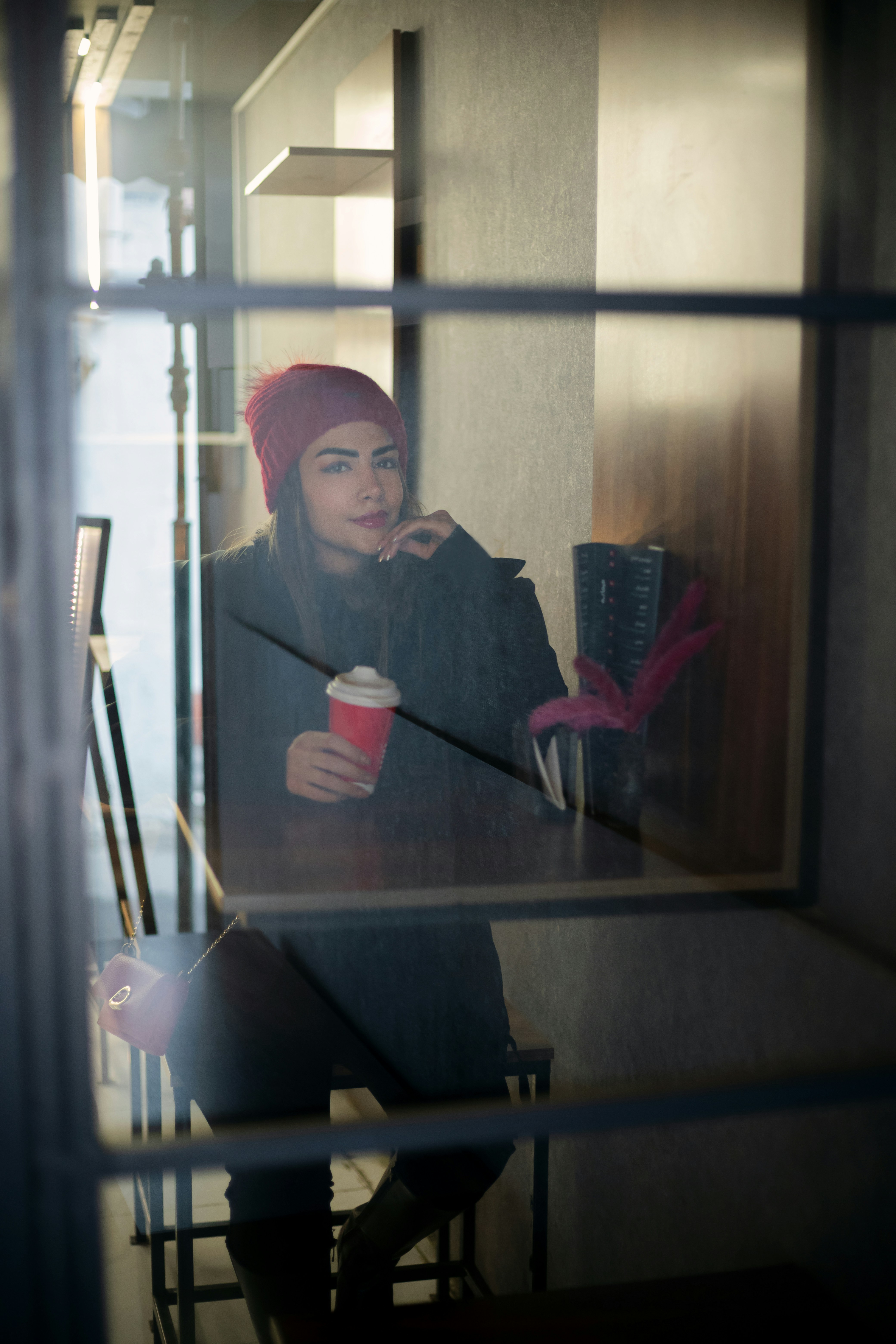 women in a cosy coffee shop looking at out the window in contemplation