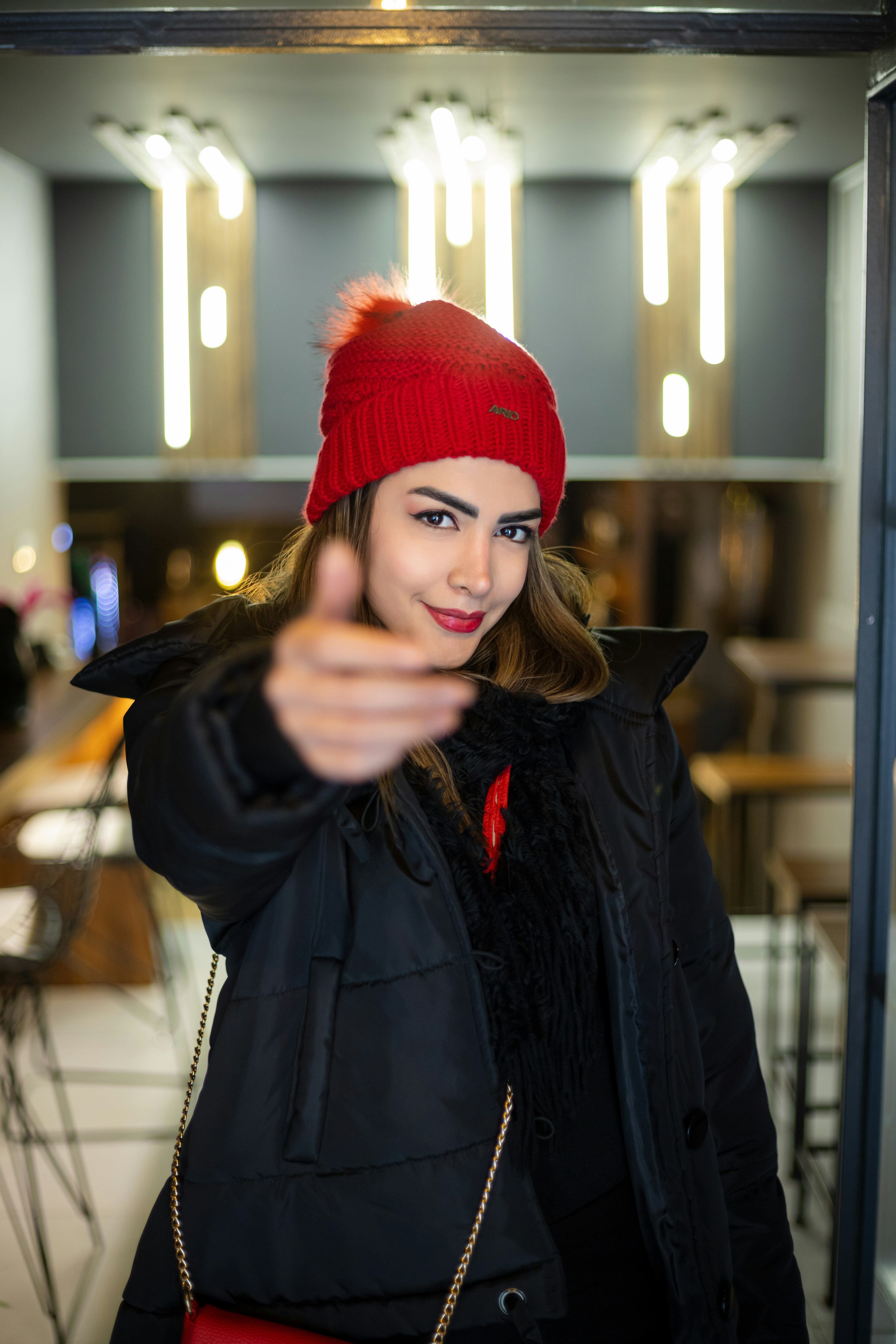 Woman in red hat beckons with her hand.