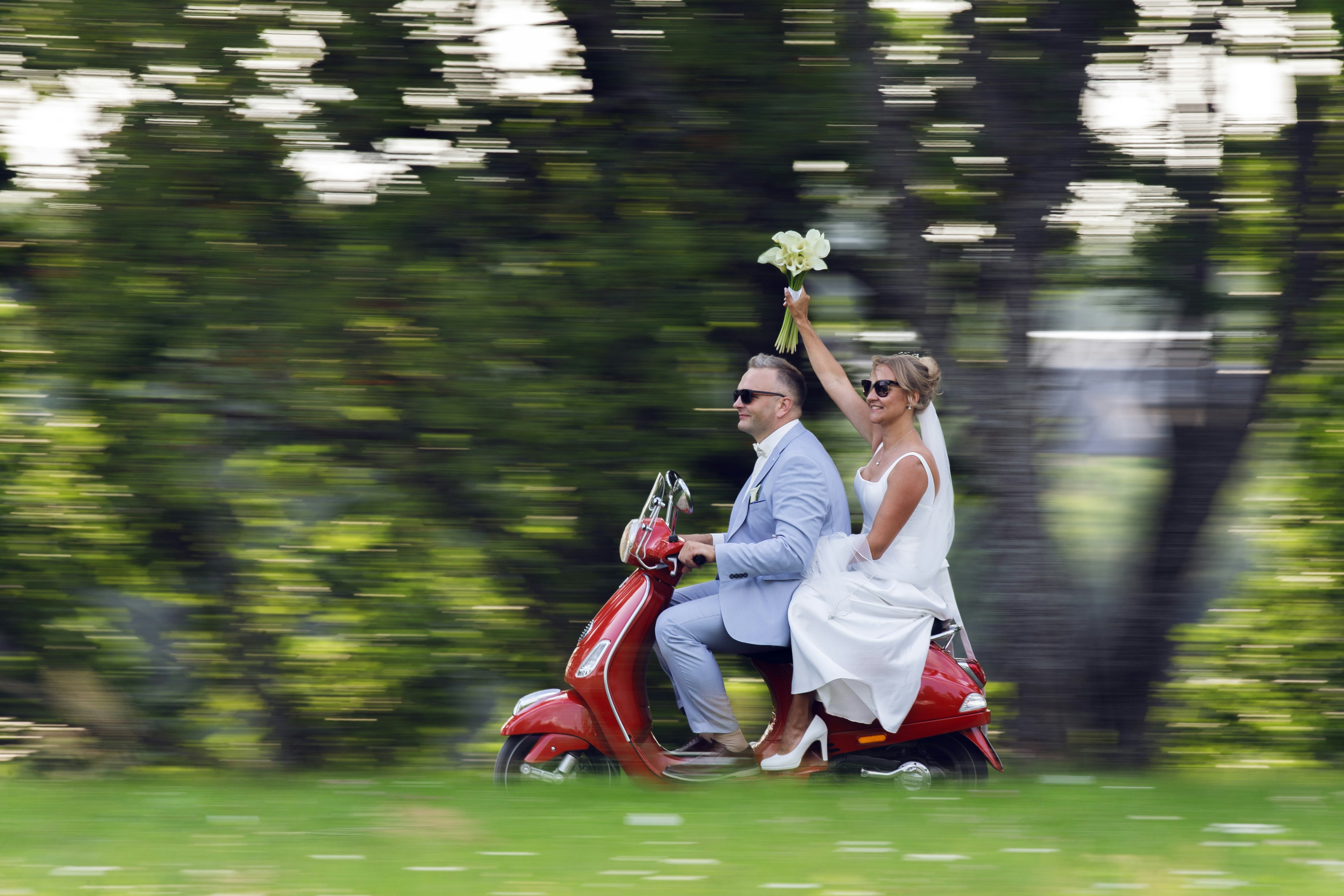 Bride and groom riding a red scooter