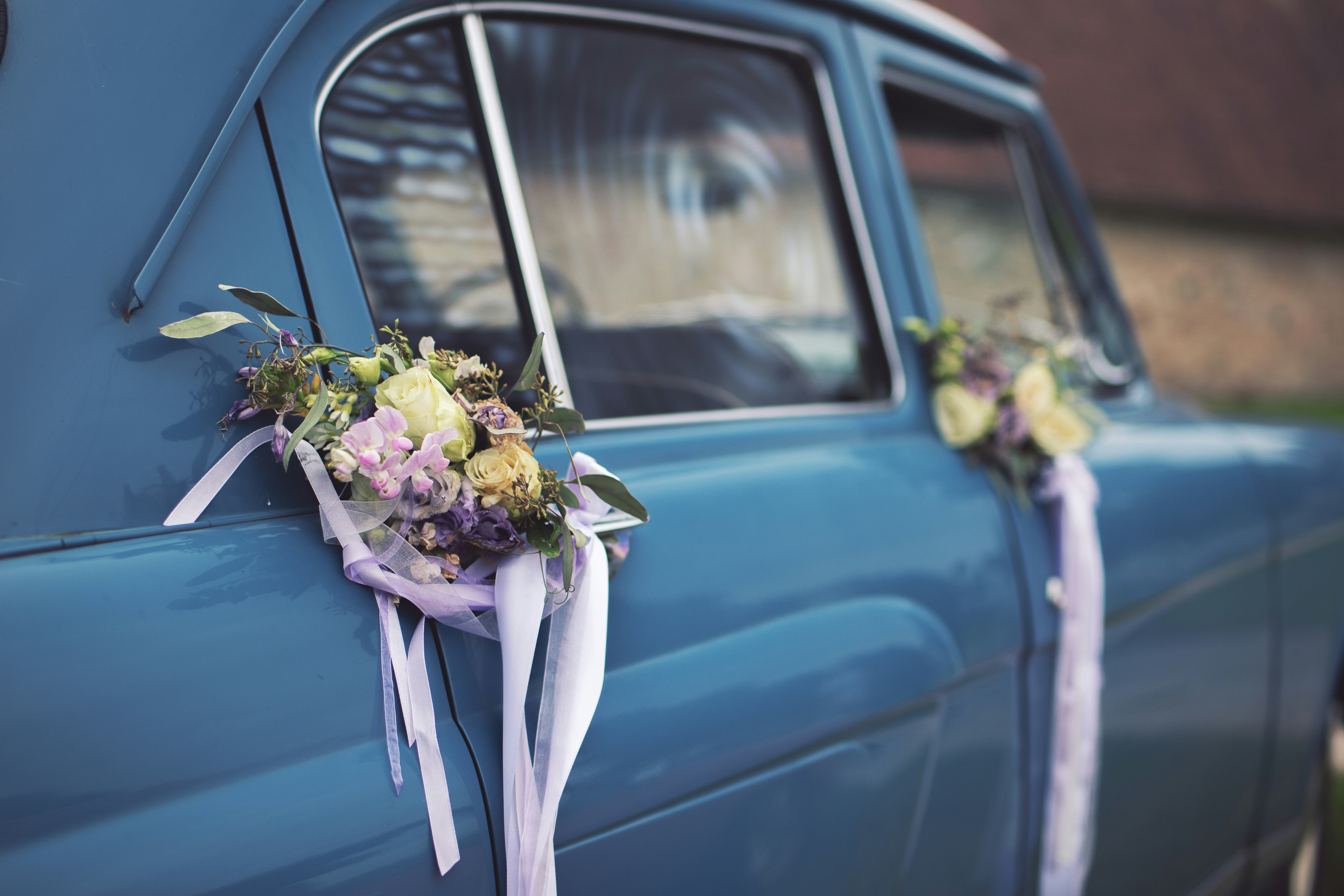 Blue vintage car decorated with floral arrangements and ribbons