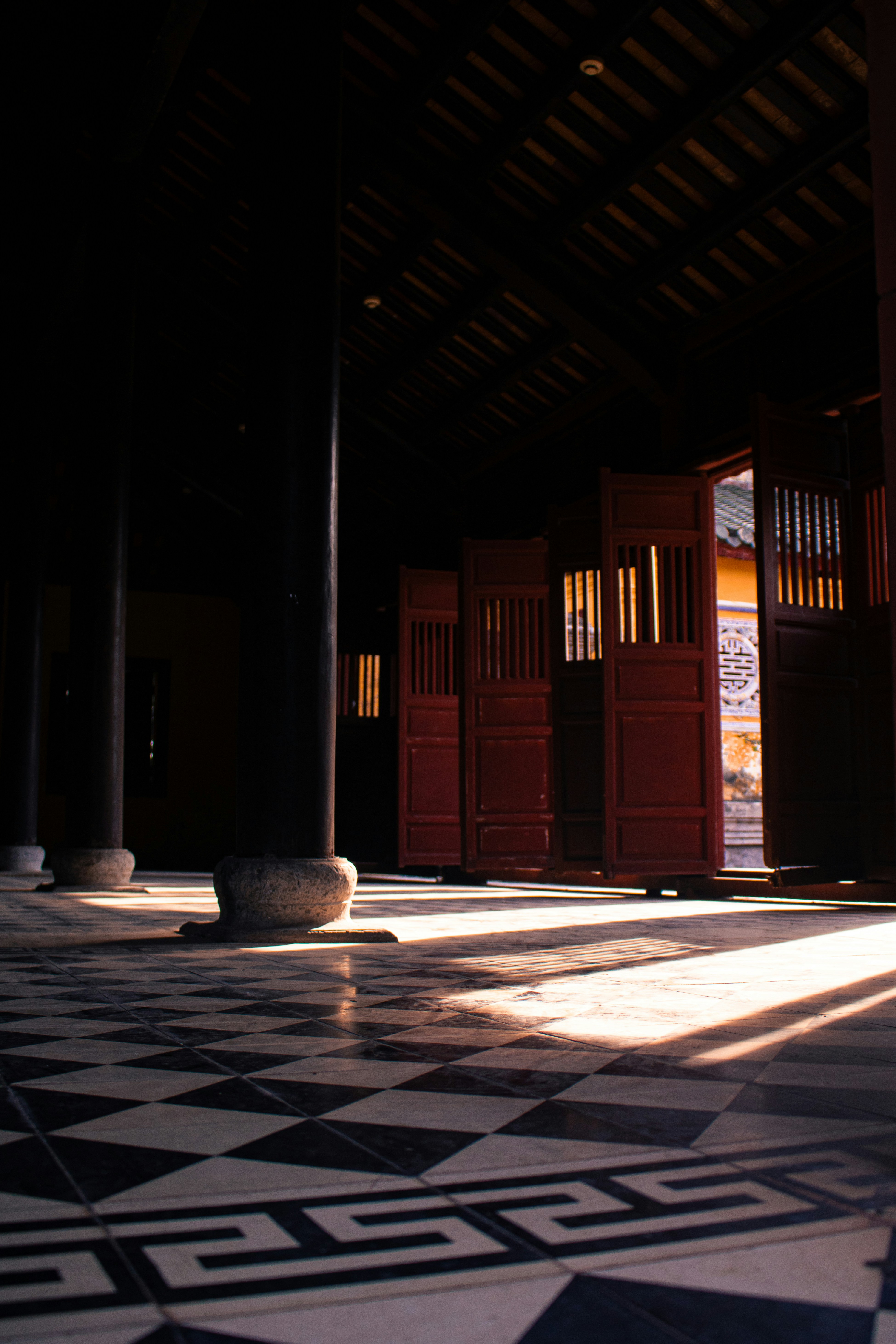 Sunlight streams through open doors in a dark hallway.