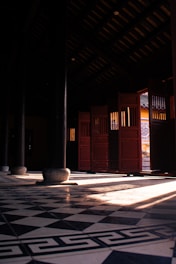 Sunlight streams through open doors in a dark hallway.