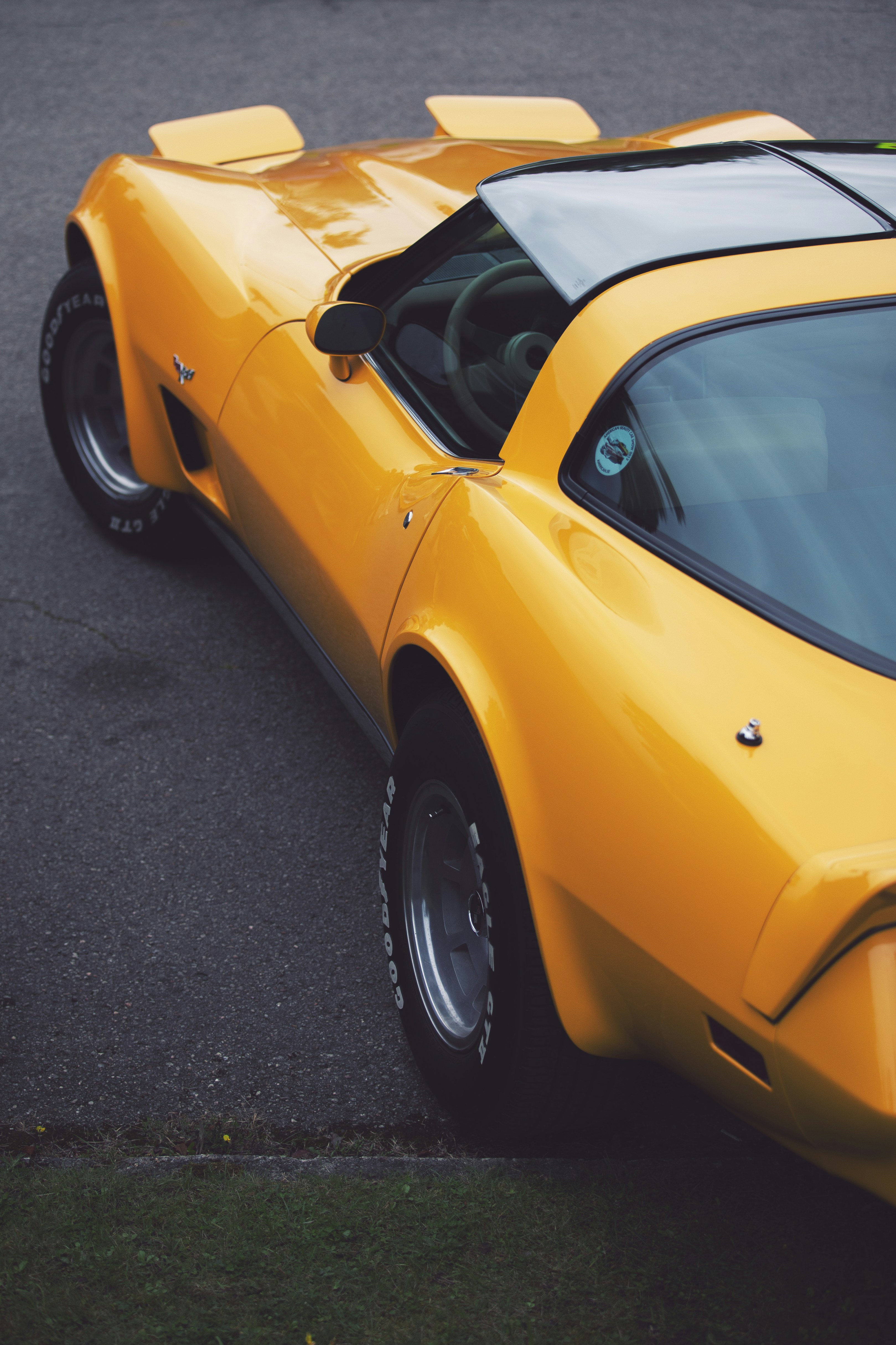 Bright yellow vintage sports car parked on asphalt.