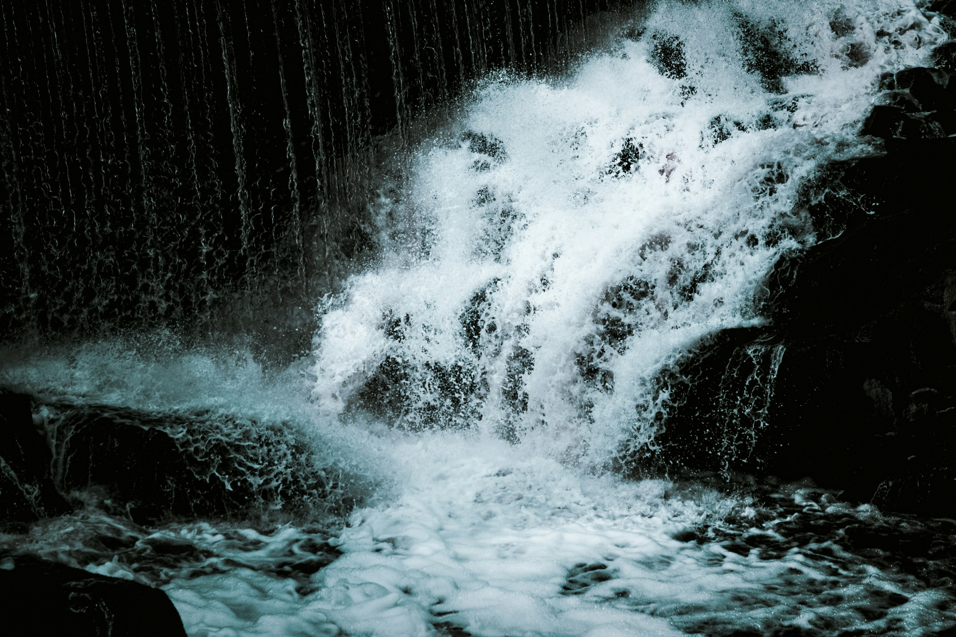 Rushing waterfall cascades over dark rocks
