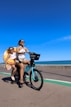 Two women ride a bicycle along the coast
