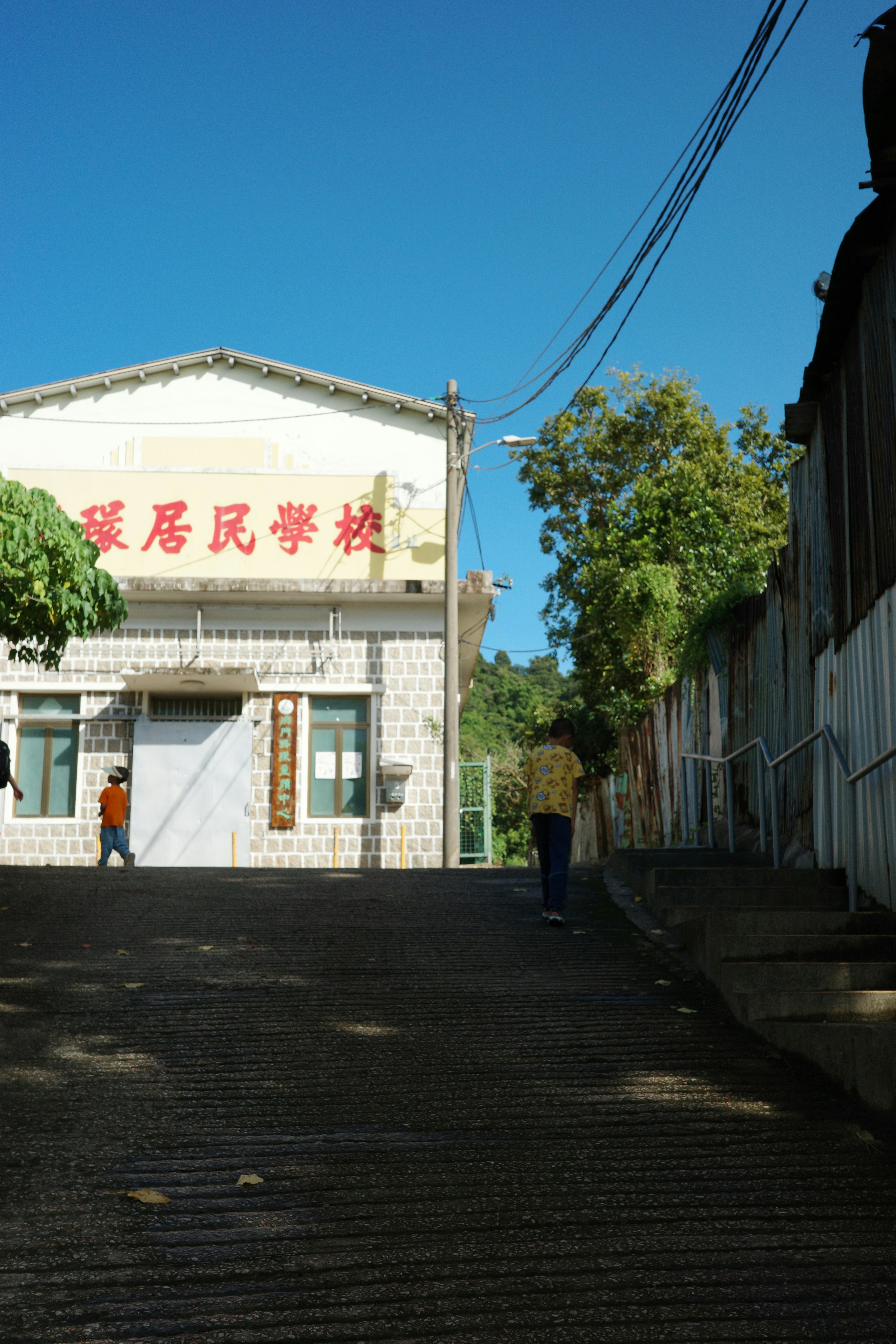 A person walks up a street towards a building.