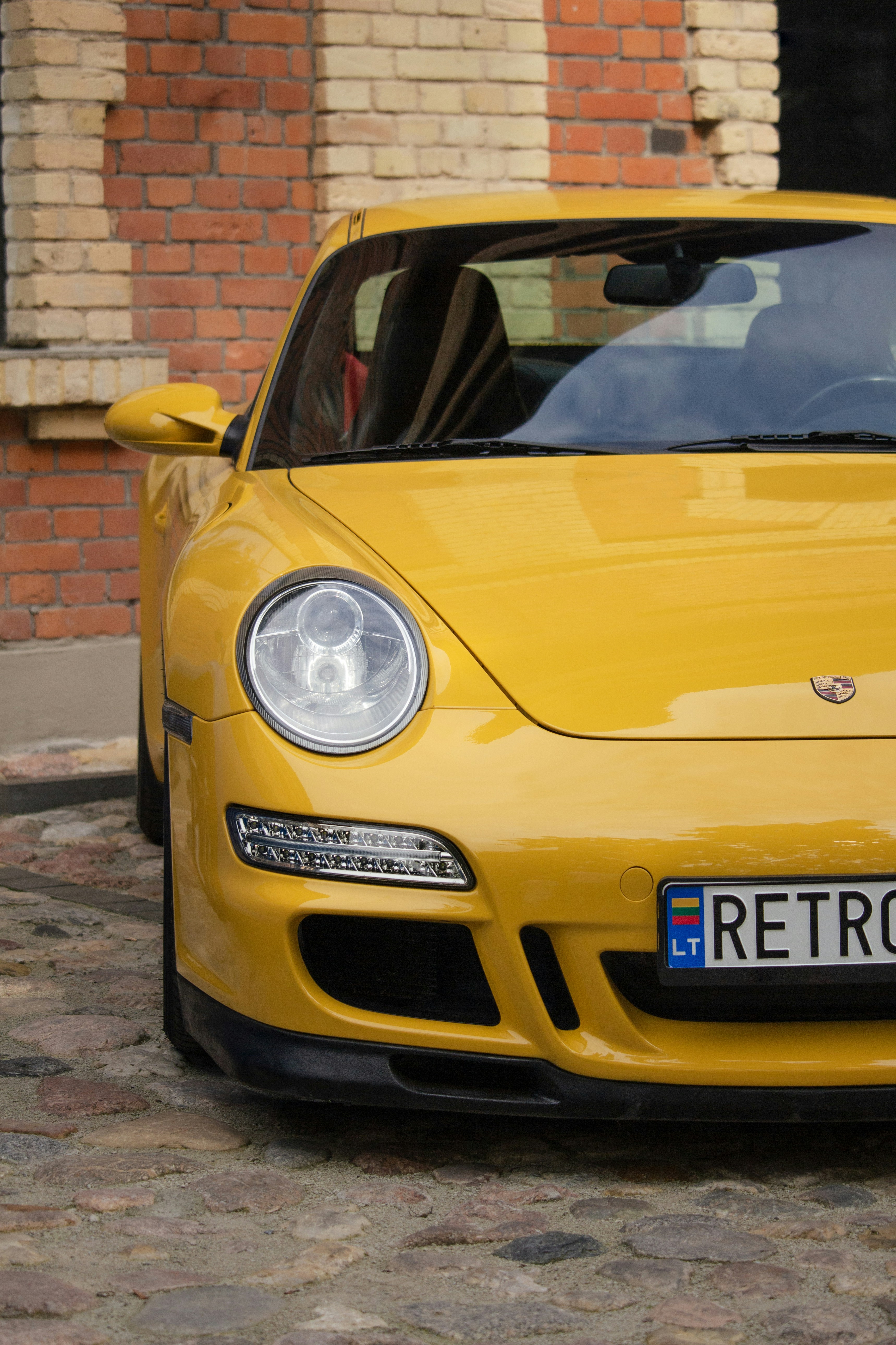 Bright yellow sports car parked on cobblestone street