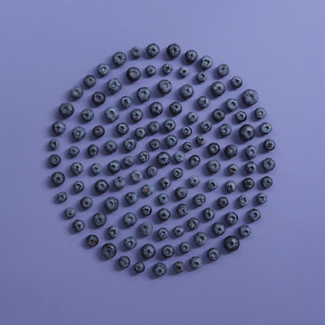 Blueberries arranged in a circular pattern on purple background