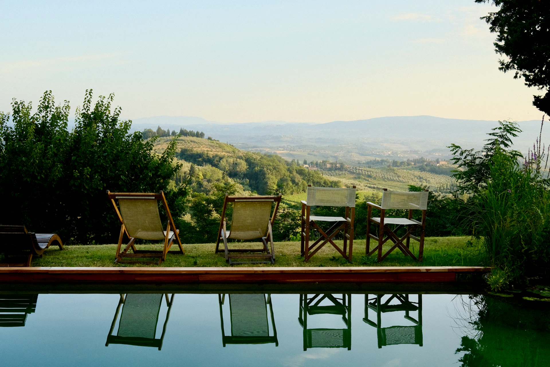 Sdraio e sedie a bordo piscina con vista sulle colline