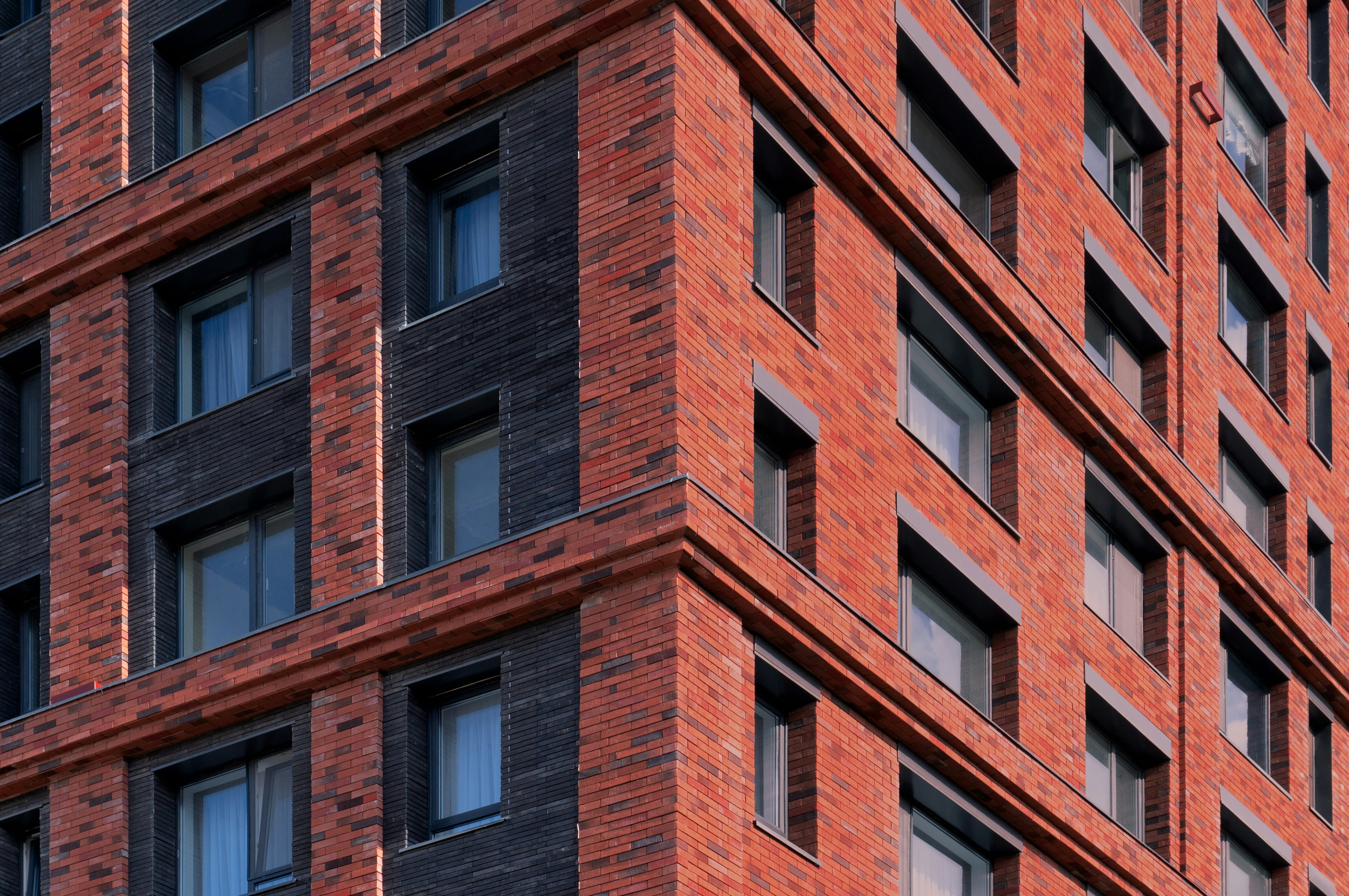 赤レンガと暗いパネルが飾られたモダンな建物の一角。