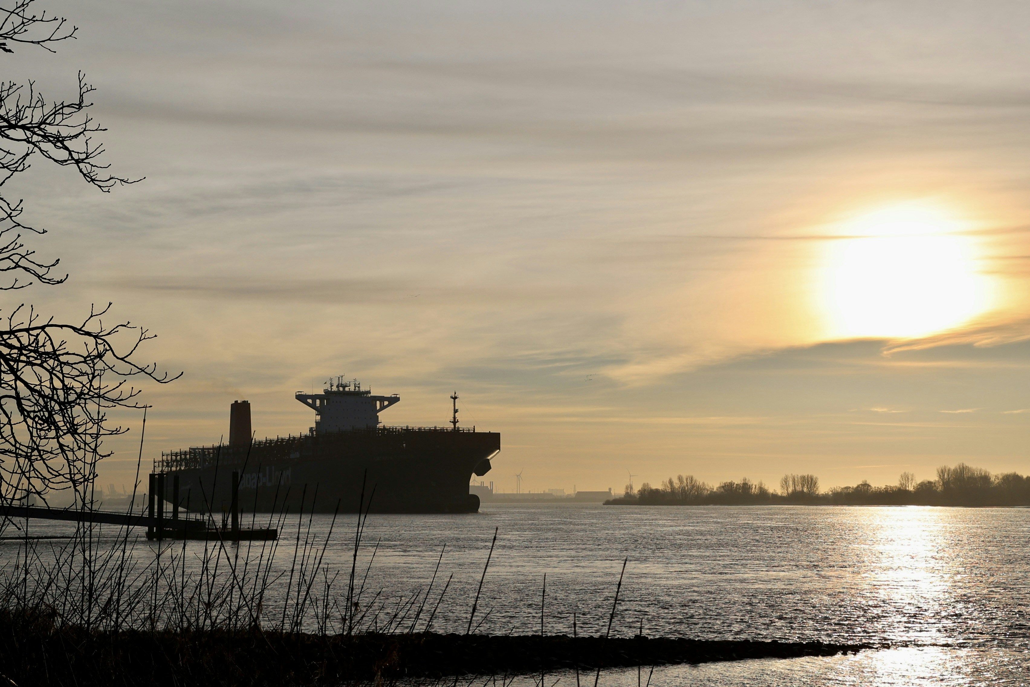 Das Frachtschiff segelt bei Sonnenuntergang auf ruhigem Wasser.