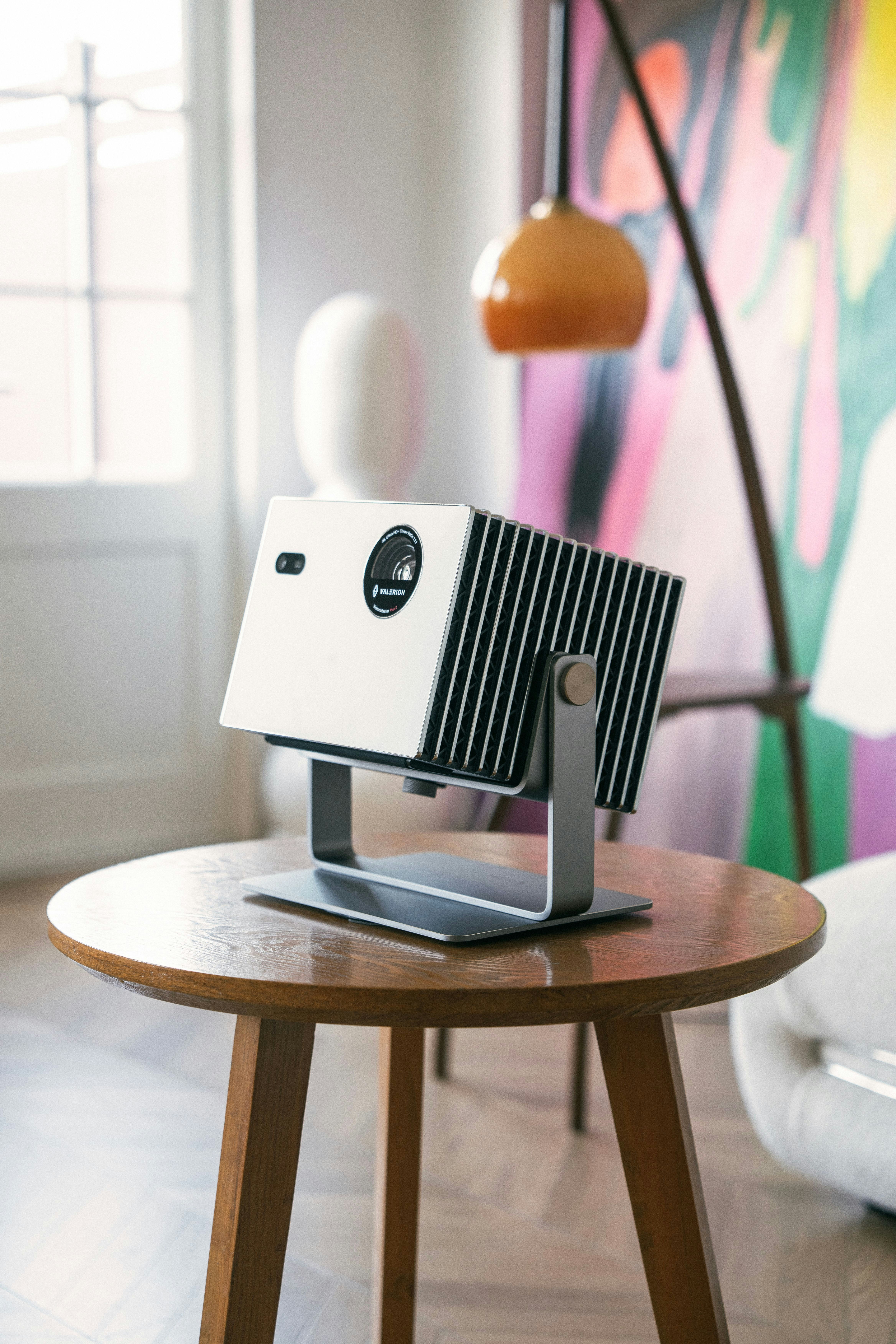 Modern projector resting on a wooden side table.