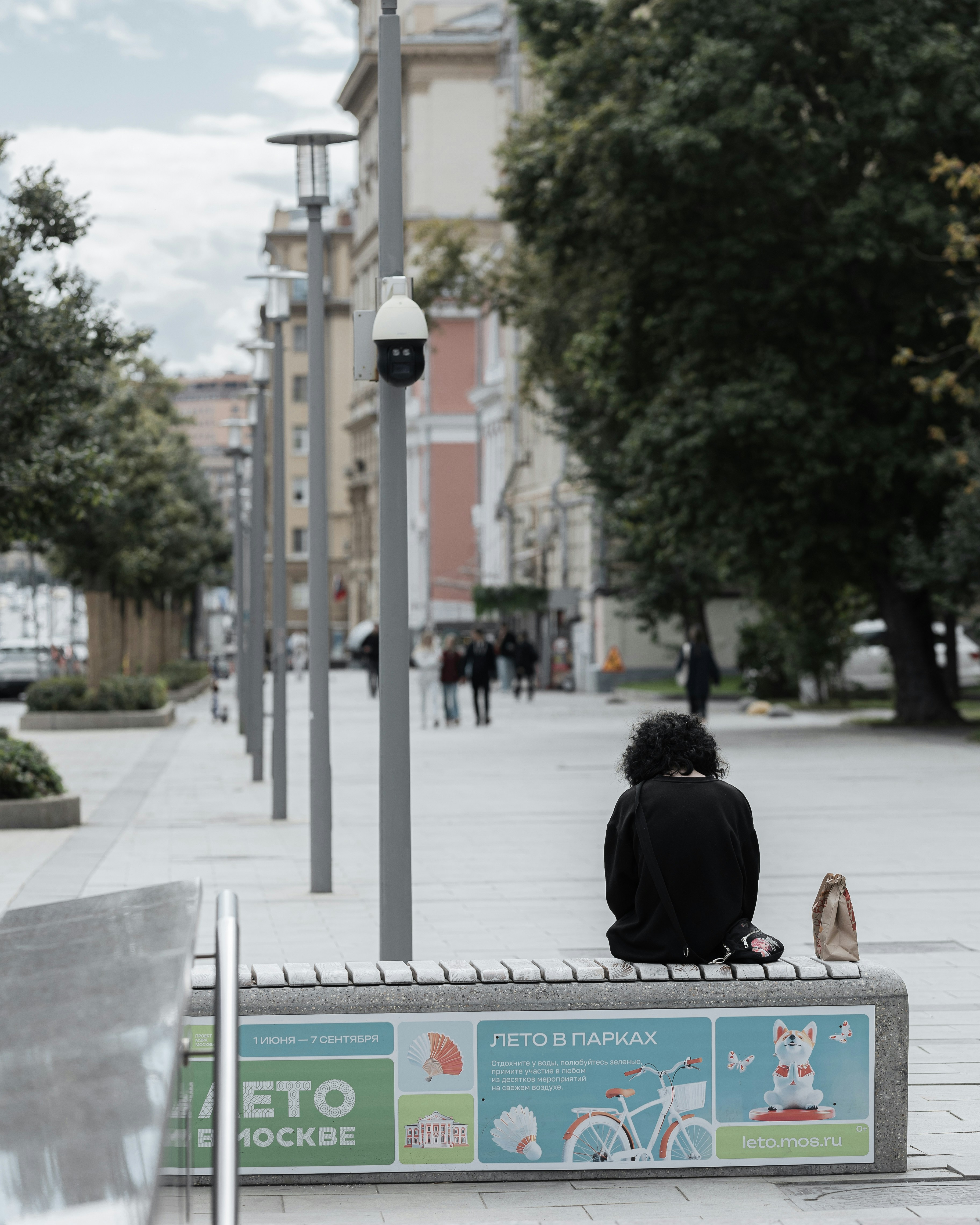 Person sitting on a bench on a city street.