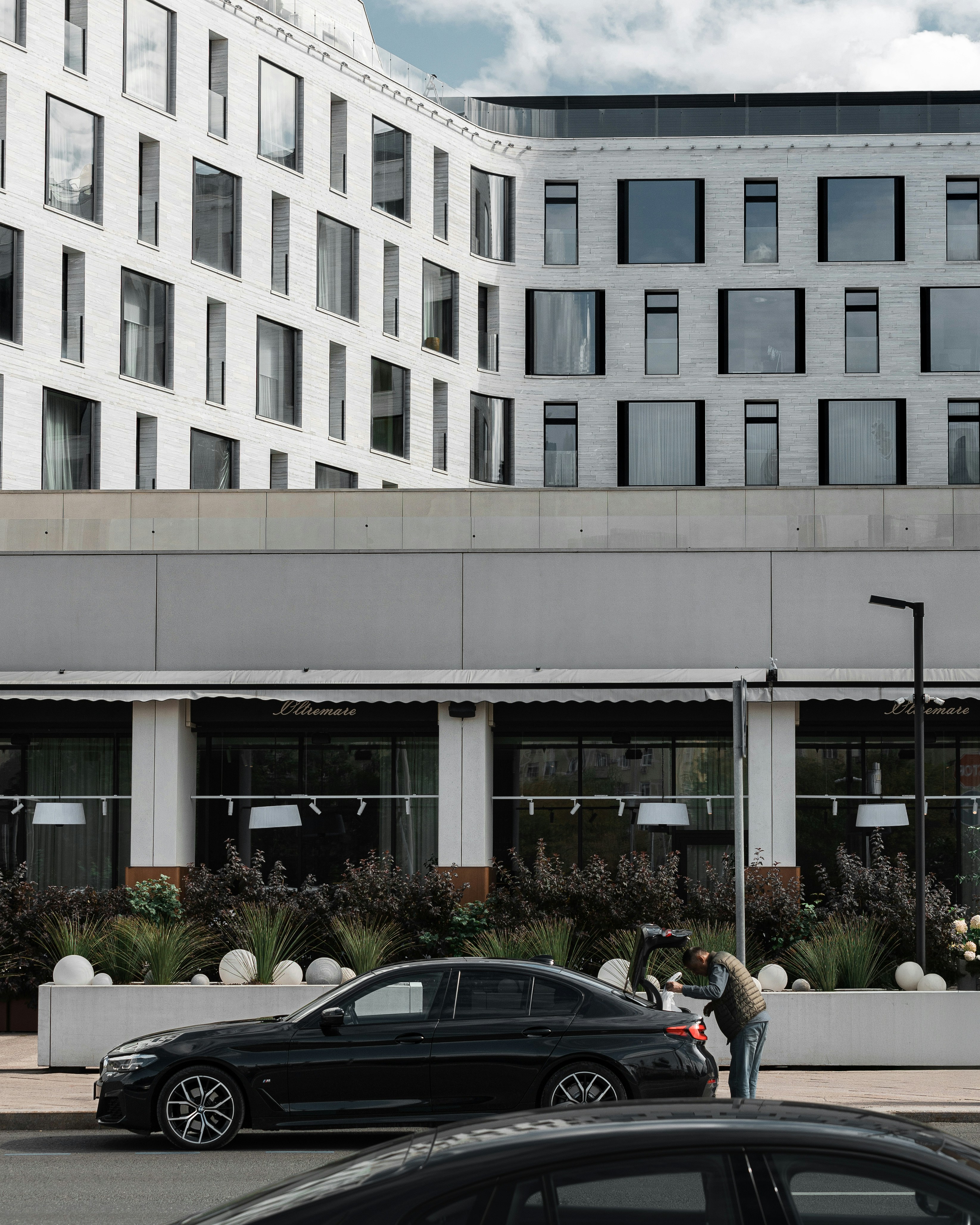 Black car parked outside modern building with windows.