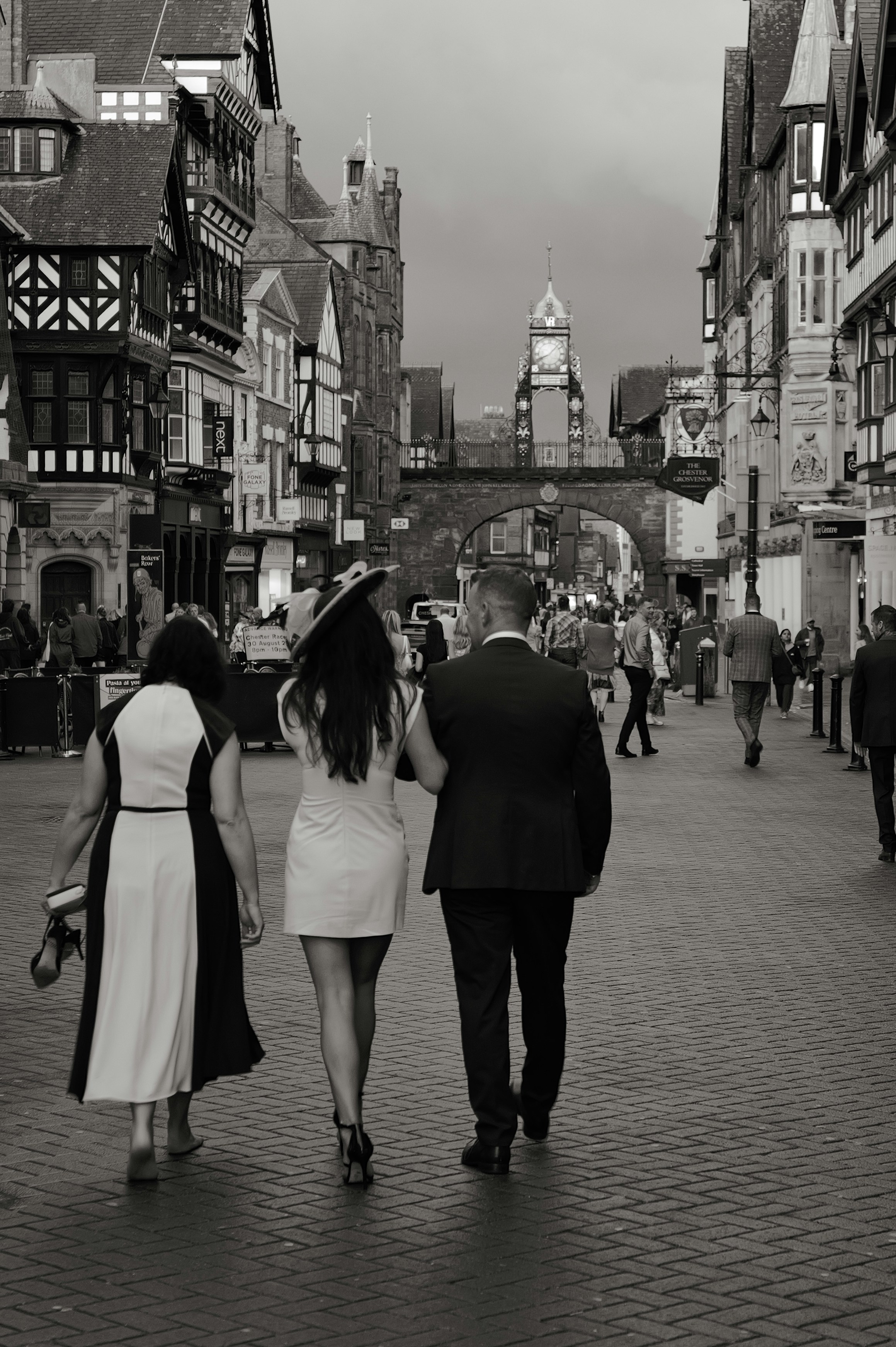 Couple walks with a companion down a street.
