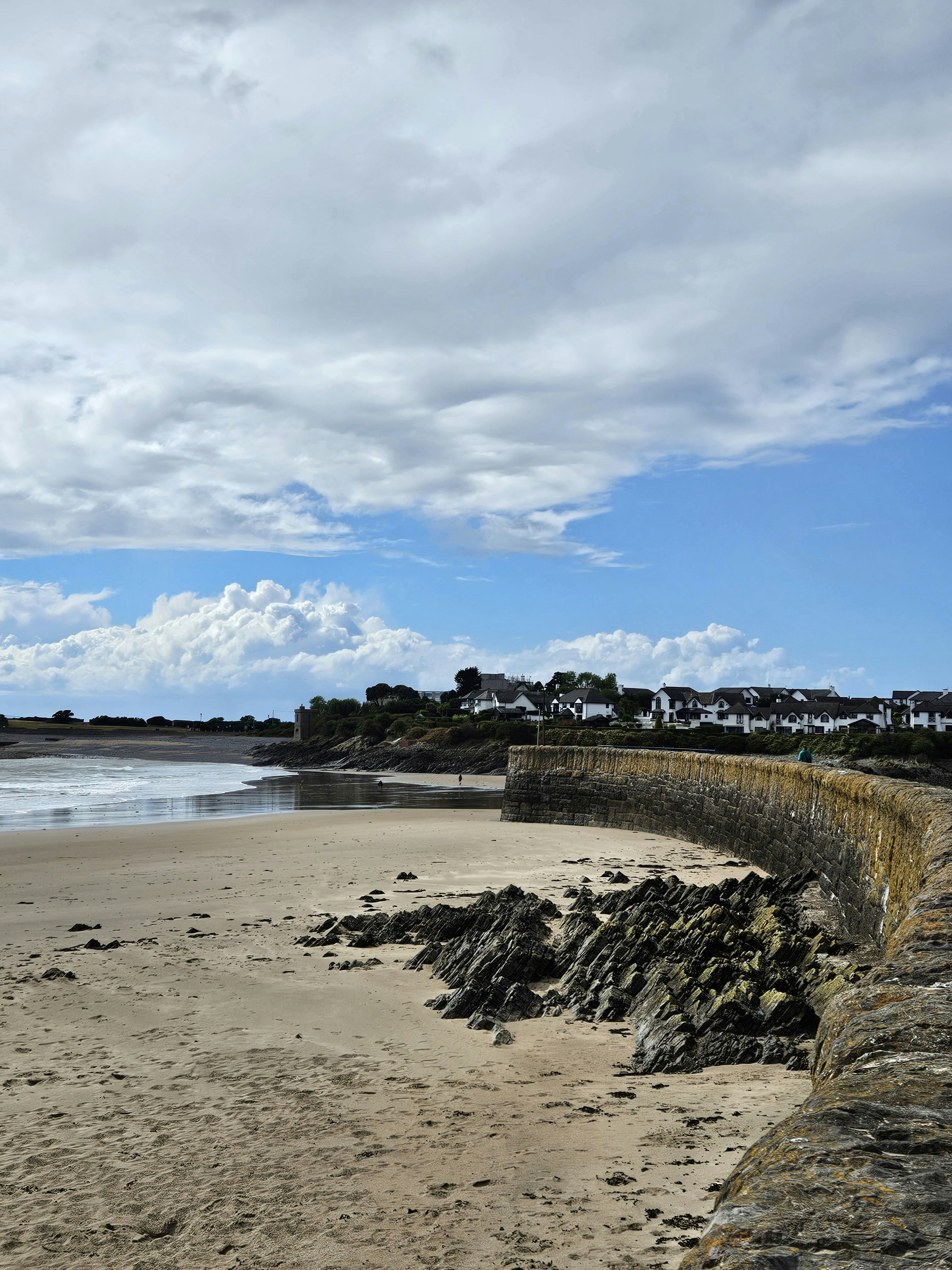 Coastal town with a curved stone sea wall and beach.