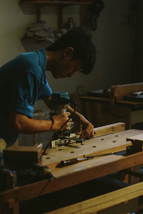 Carpenter using a router on wood at workbench