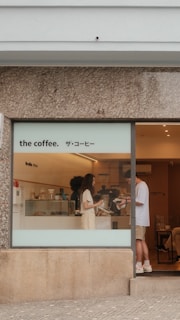 People at a coffee shop counter with signage.