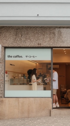 People at a coffee shop counter with signage.