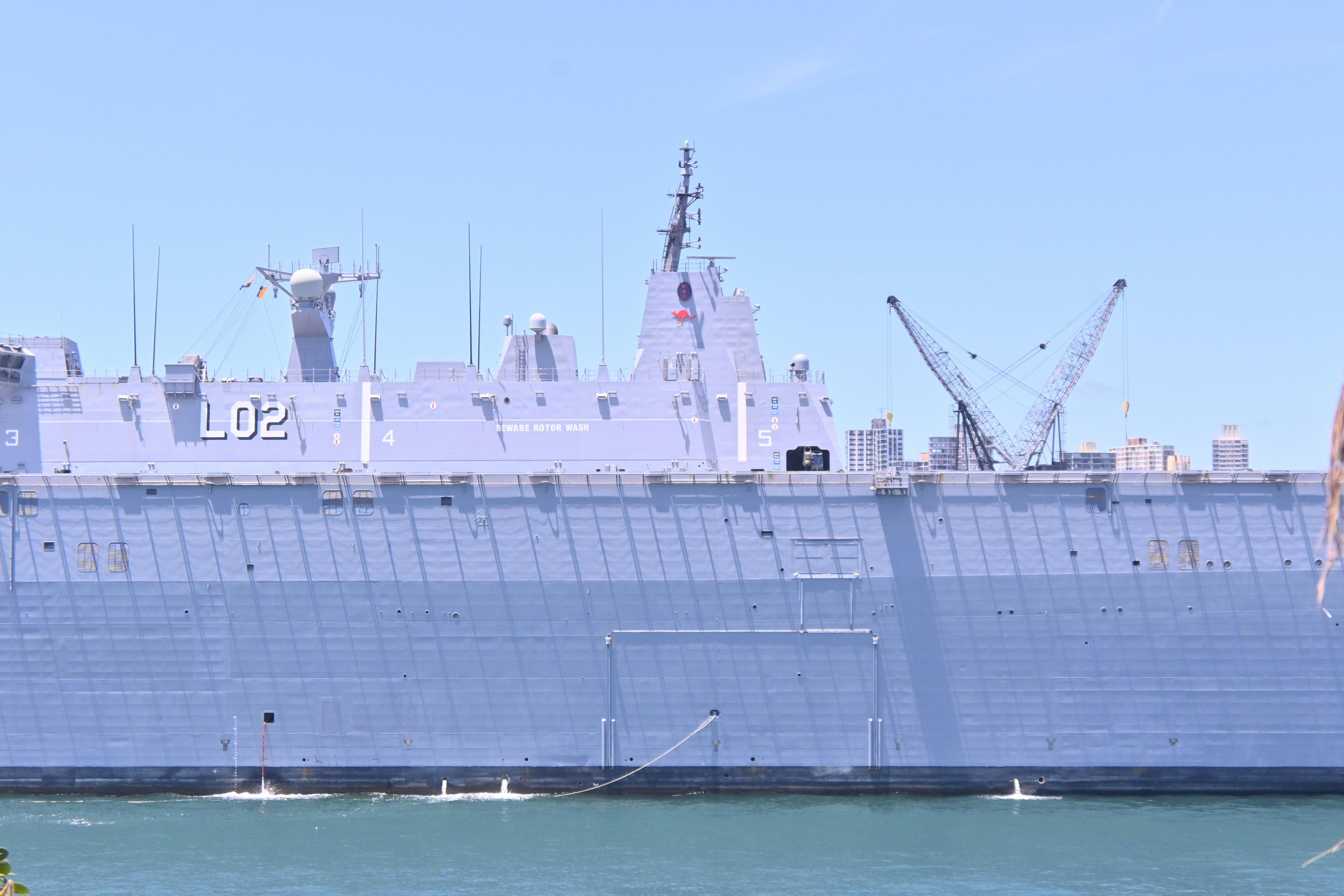 Large gray naval ship docked in harbor