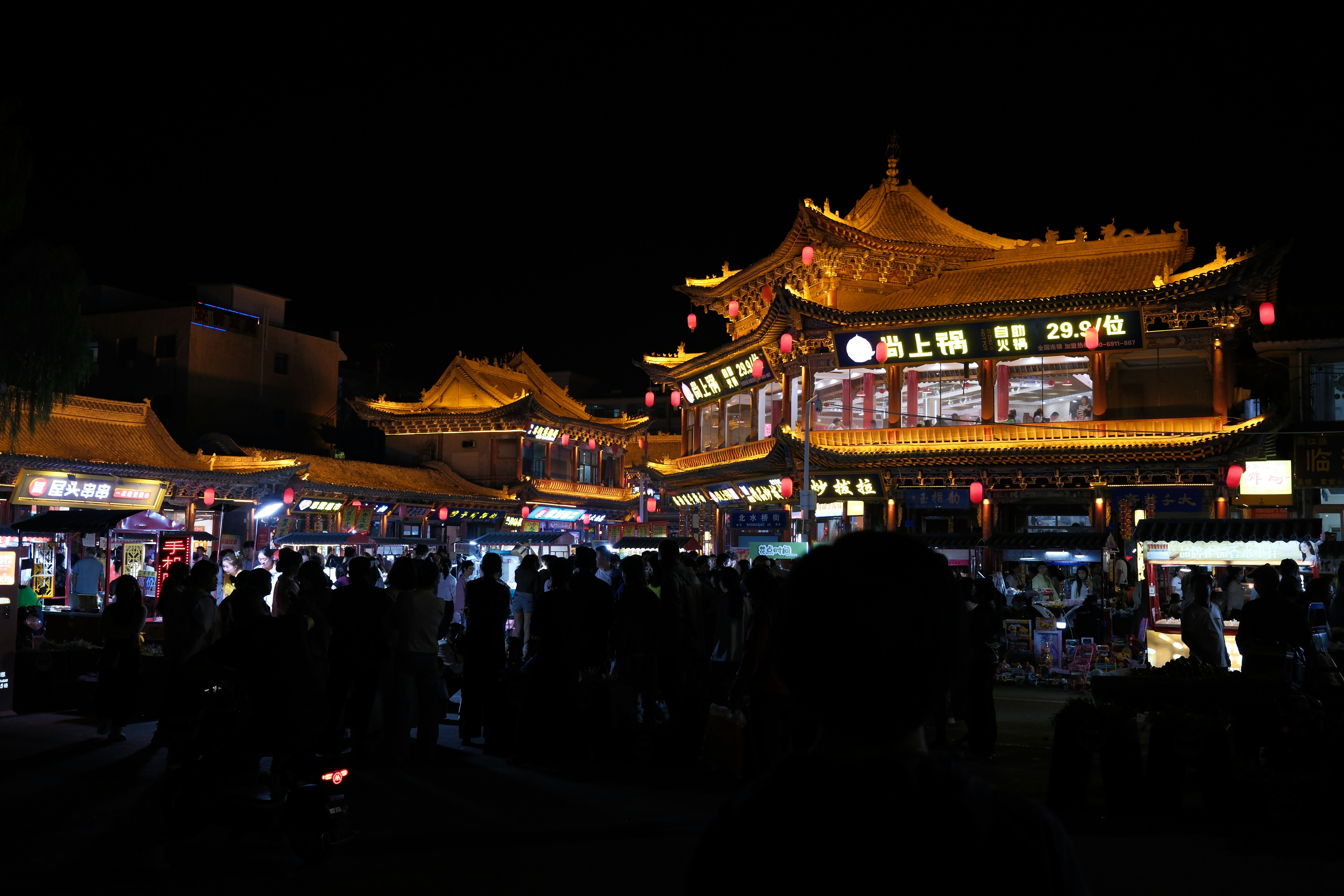 Traditional asian buildings illuminated at night with crowds.