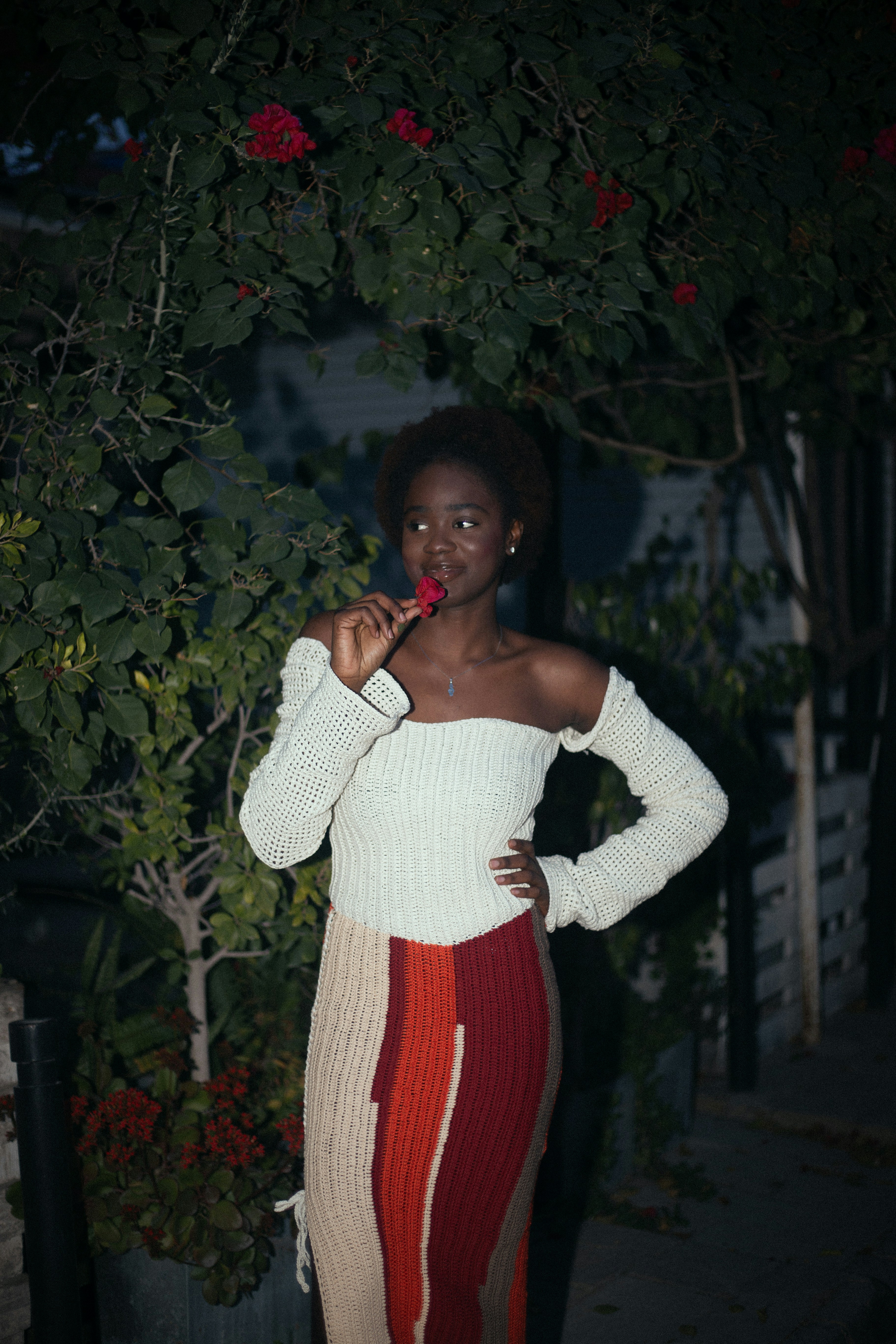 Woman in off-the-shoulder top holds red flower