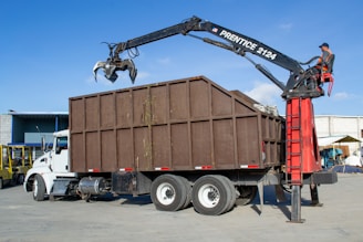 Crane truck loading debris into a large bin.