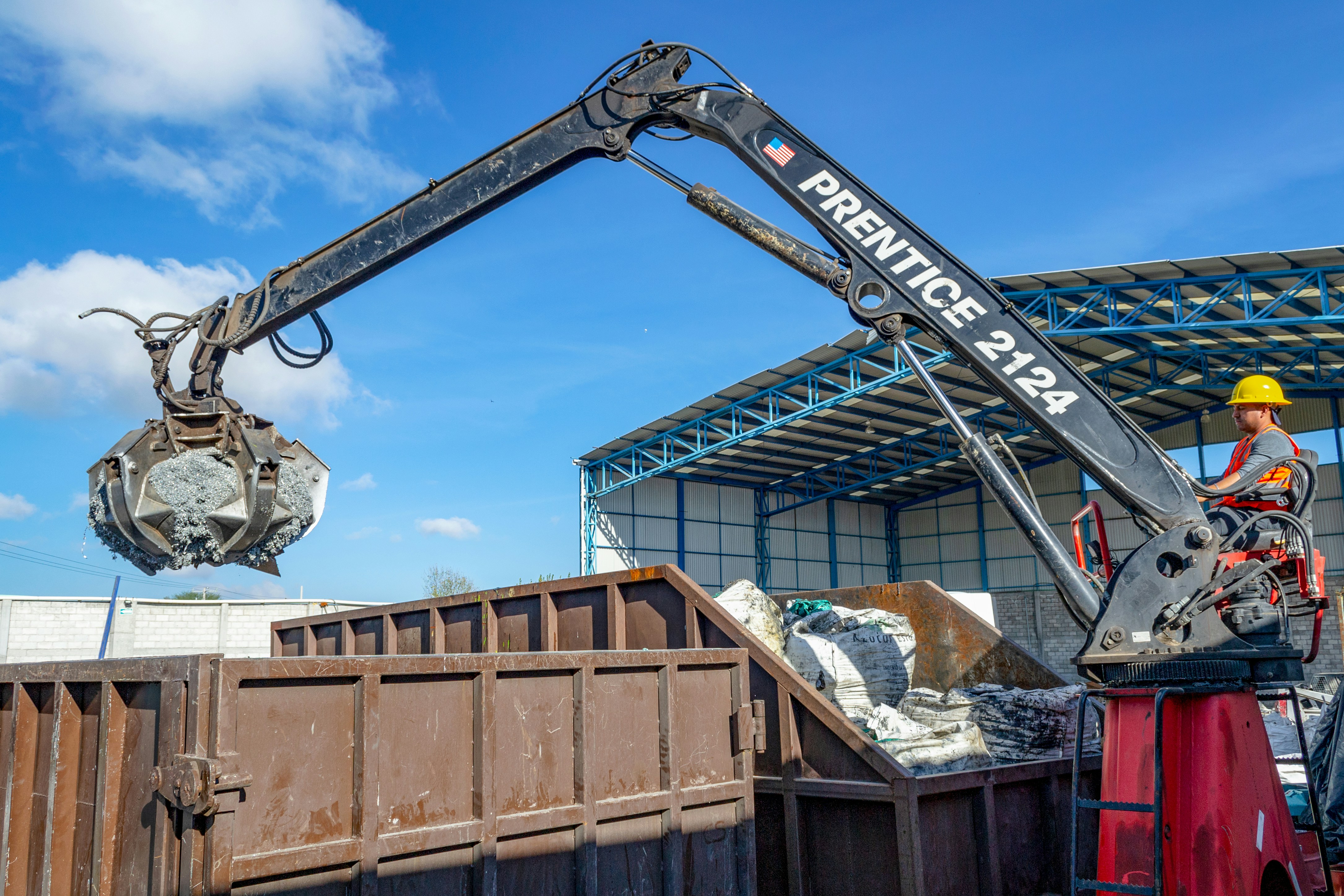 Crane loading debris into a large roll-off dumpster at a construction site in Jacksonville, photo by Alethia Briones on Unsplash
