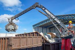 Crane with grapple loading debris into a dumpster
