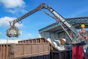 Crane with grapple loading debris into a dumpster
