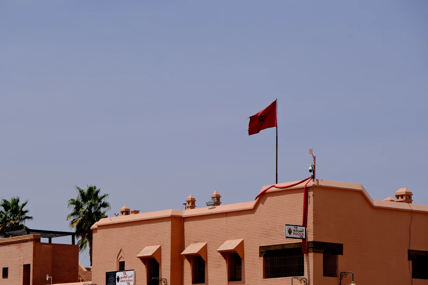 Moroccan flag flying against a terracotta building, symbol of national investment ahead of the World Cup 2030