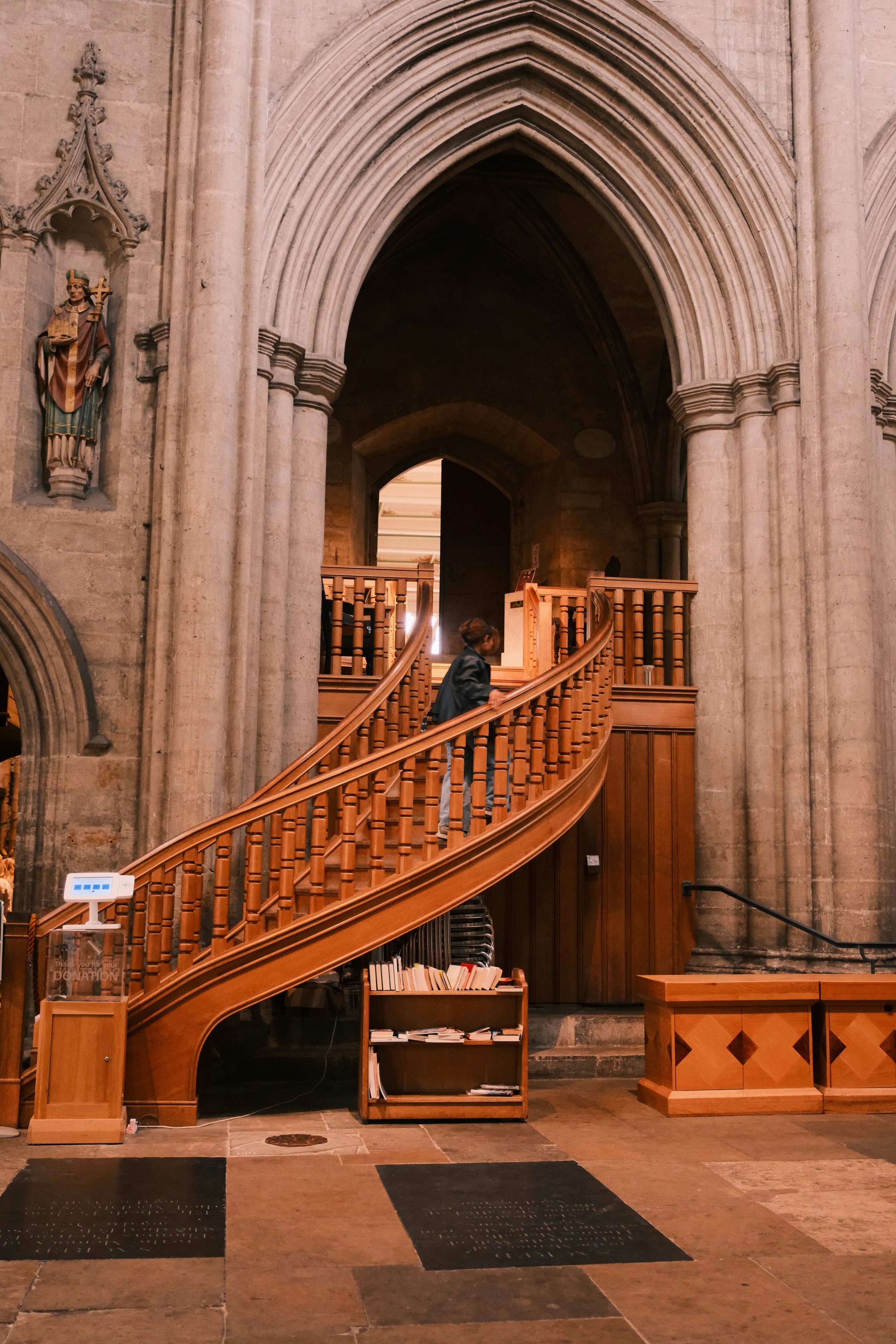 Person climbing wooden spiral staircase inside church