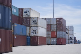 Stacks of shipping containers at a port under a blue sky