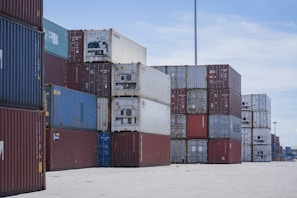 Stacks of shipping containers at a port under a blue sky