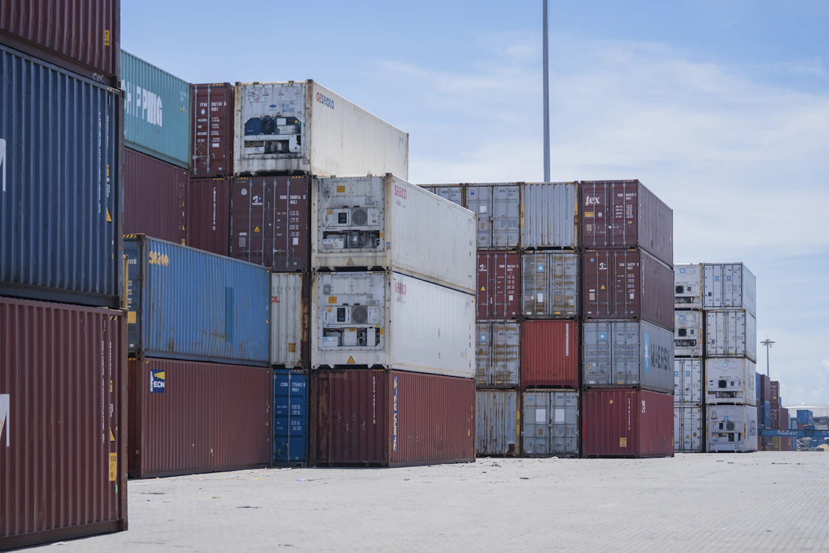 Stacks of colorful shipping containers at a port under a blue sky, mirroring Docker's own container metaphor for portable, self-contained software