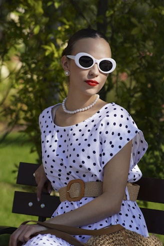 Woman in polka dots and sunglasses sits on bench