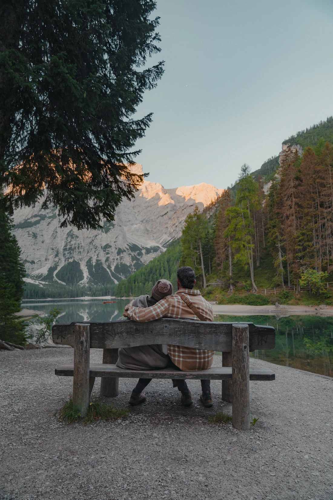 Older couple sitting on a bench overlooking a mountain lake