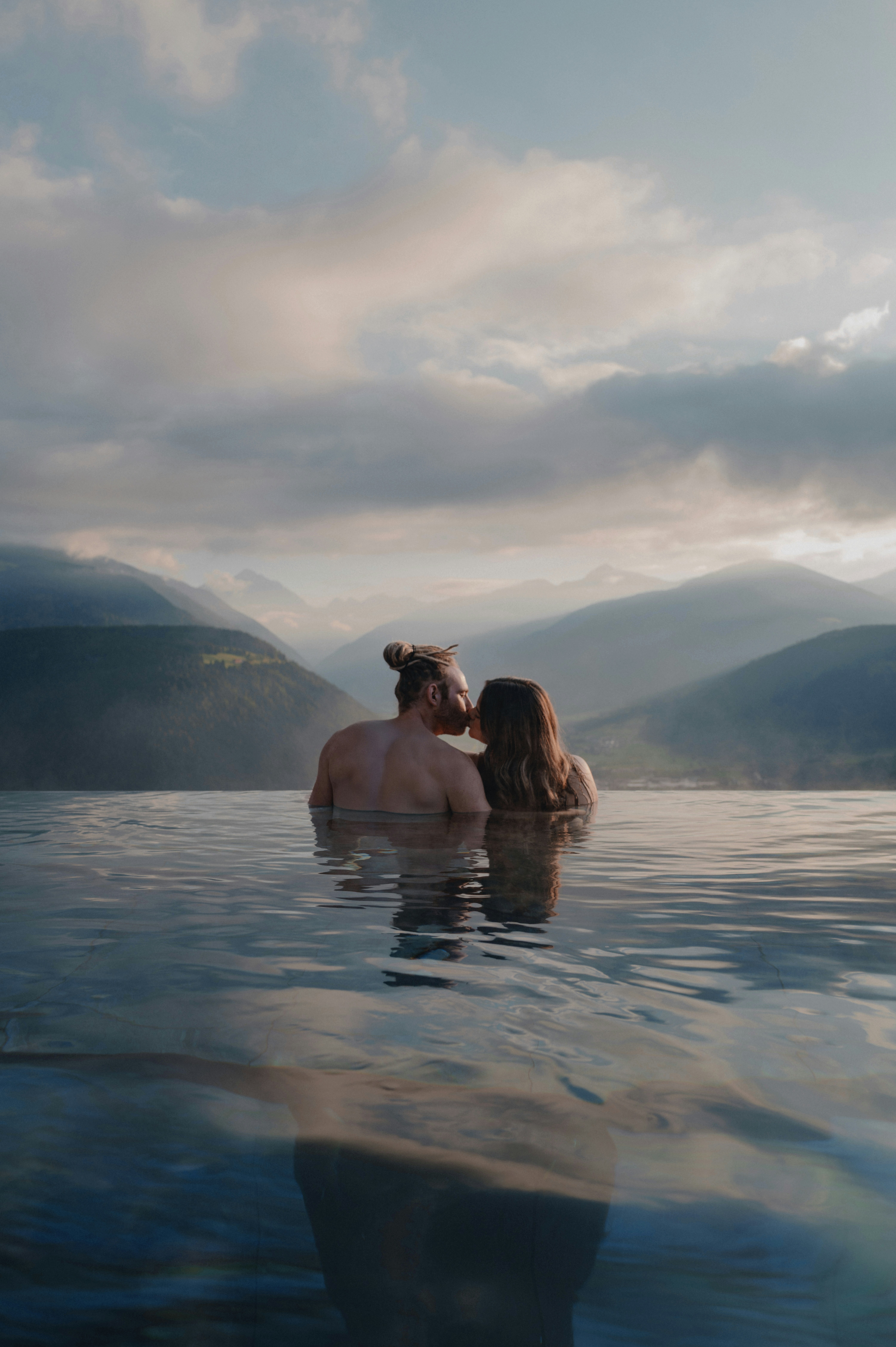 Couple kissing in a serene mountain lake at sunset