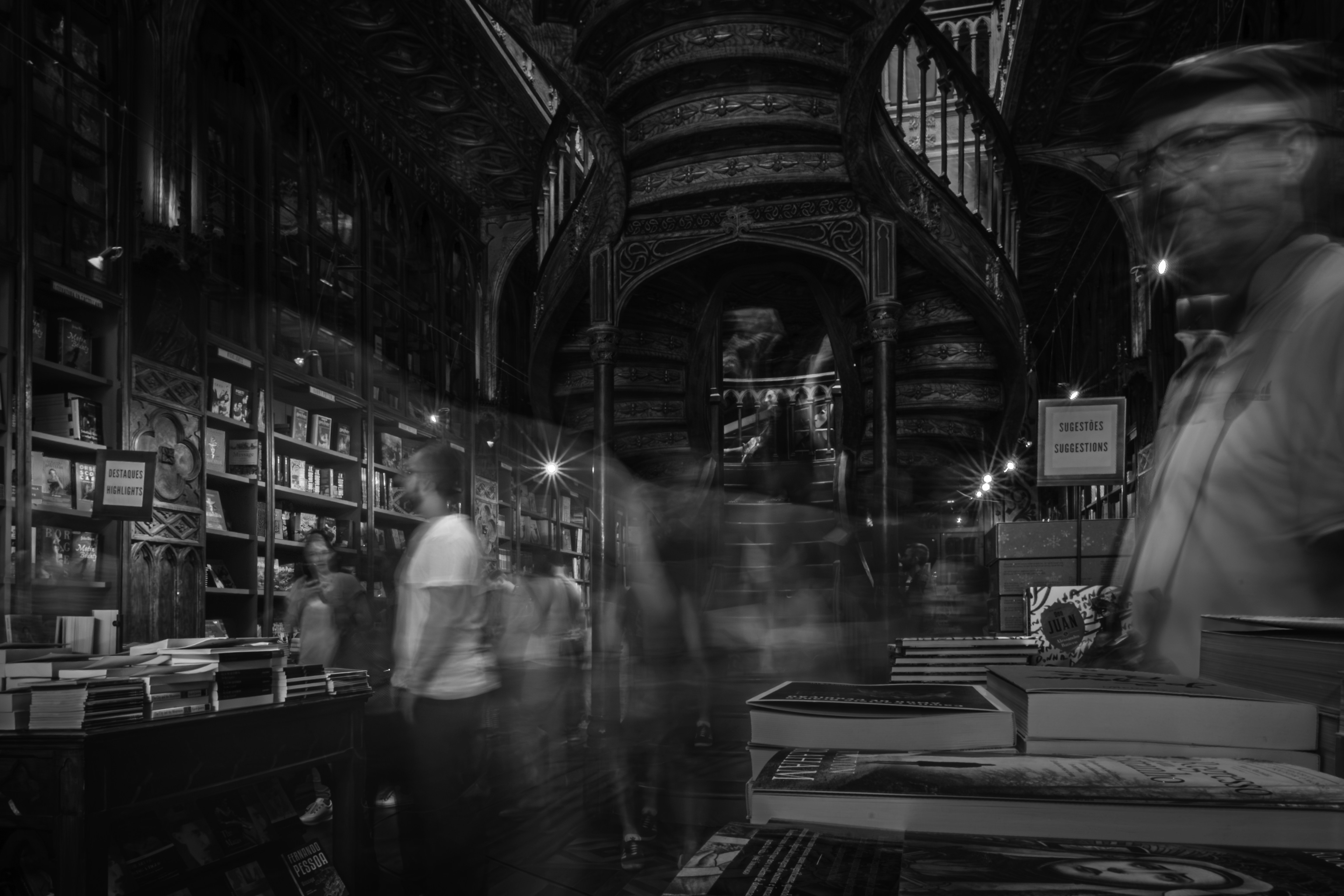 Blurry figures in a vintage bookstore with spiral staircase