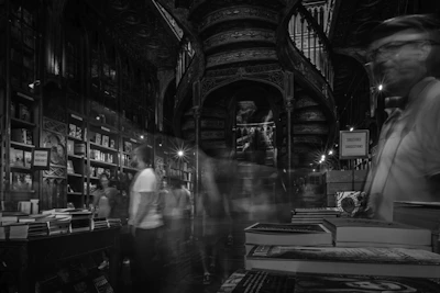 Blurry figures in a vintage bookstore with spiral staircase