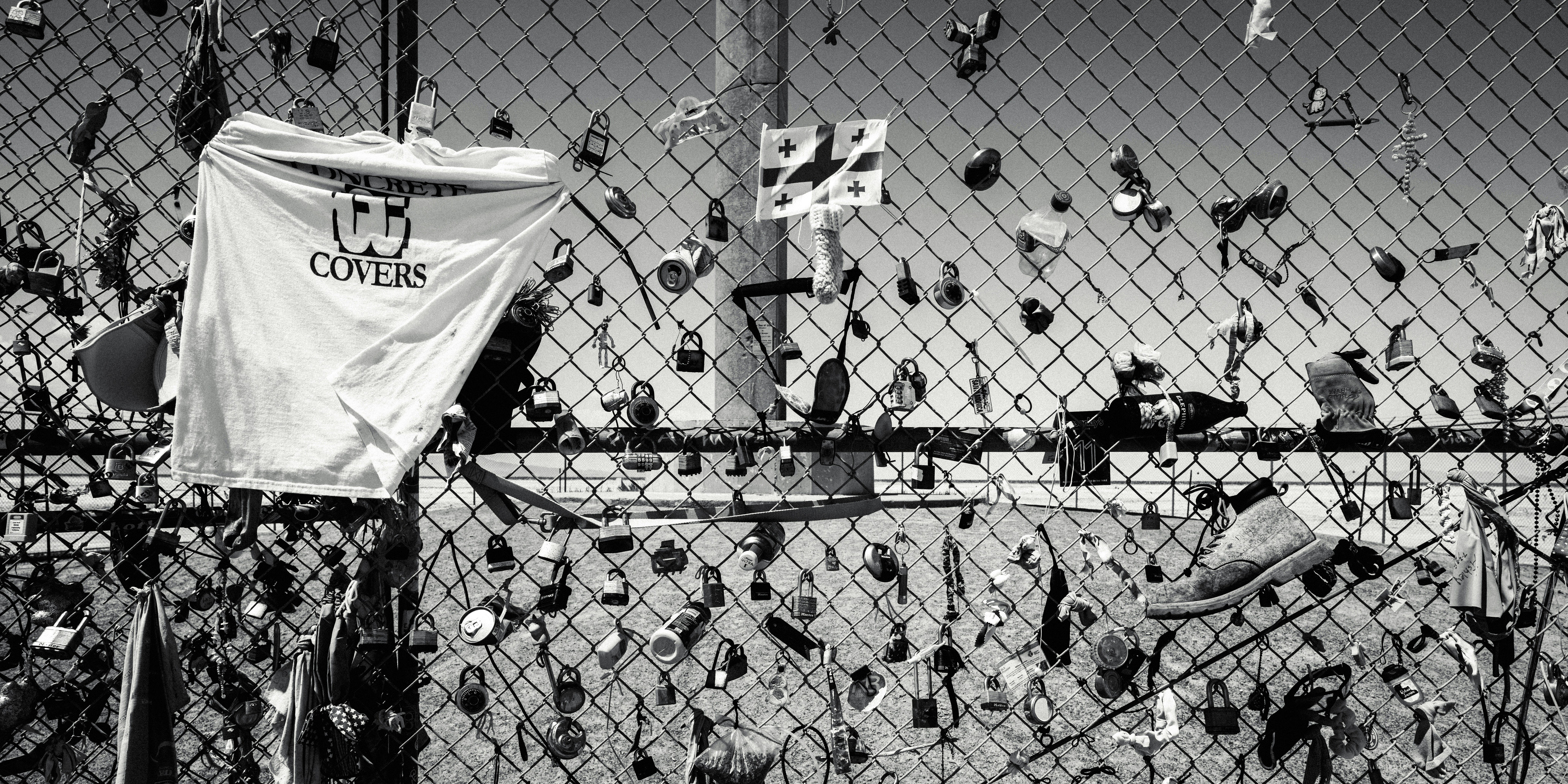 A fence covered in locks and a white shirt.