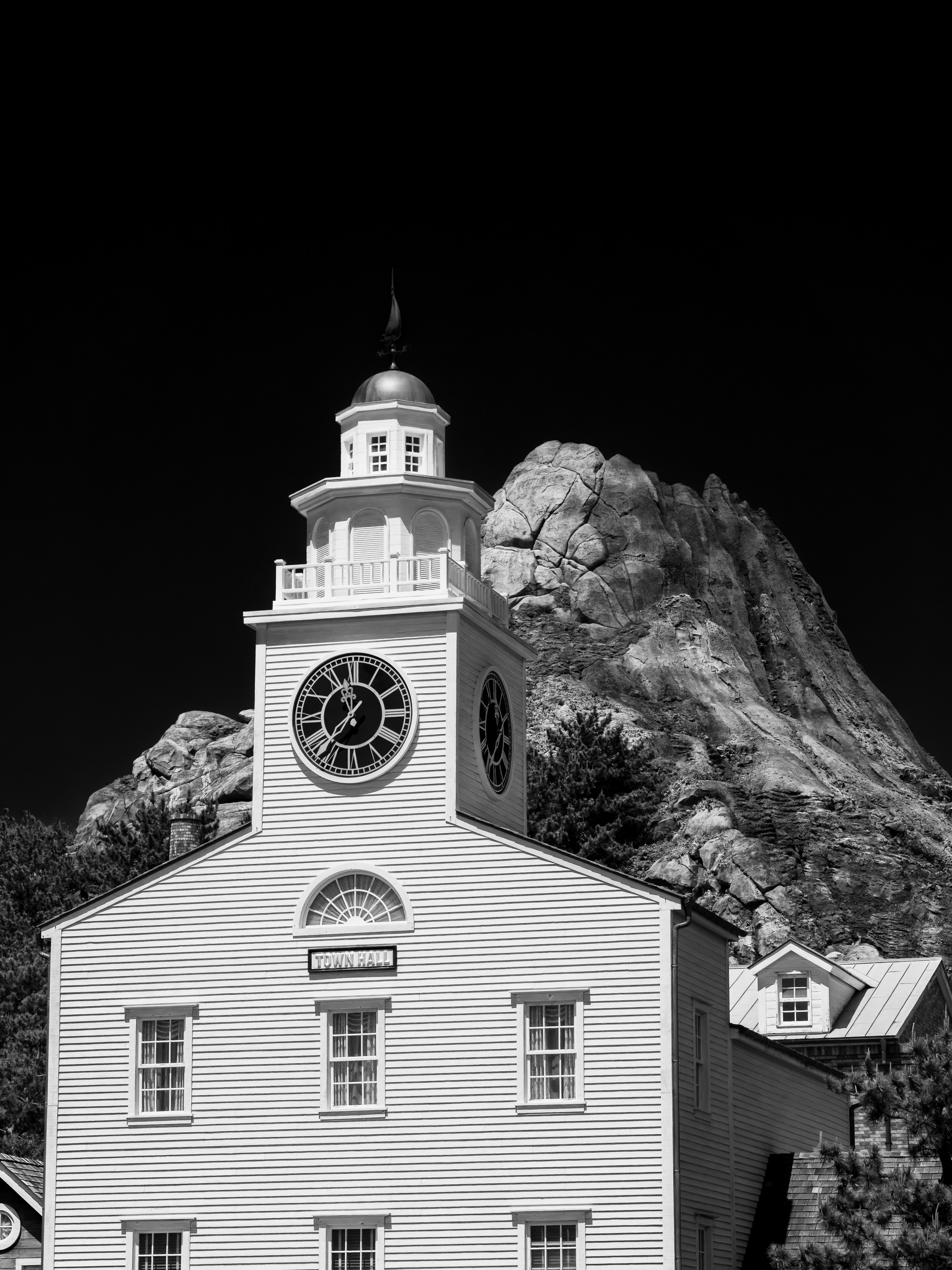 White building with clock tower and rocky mountain