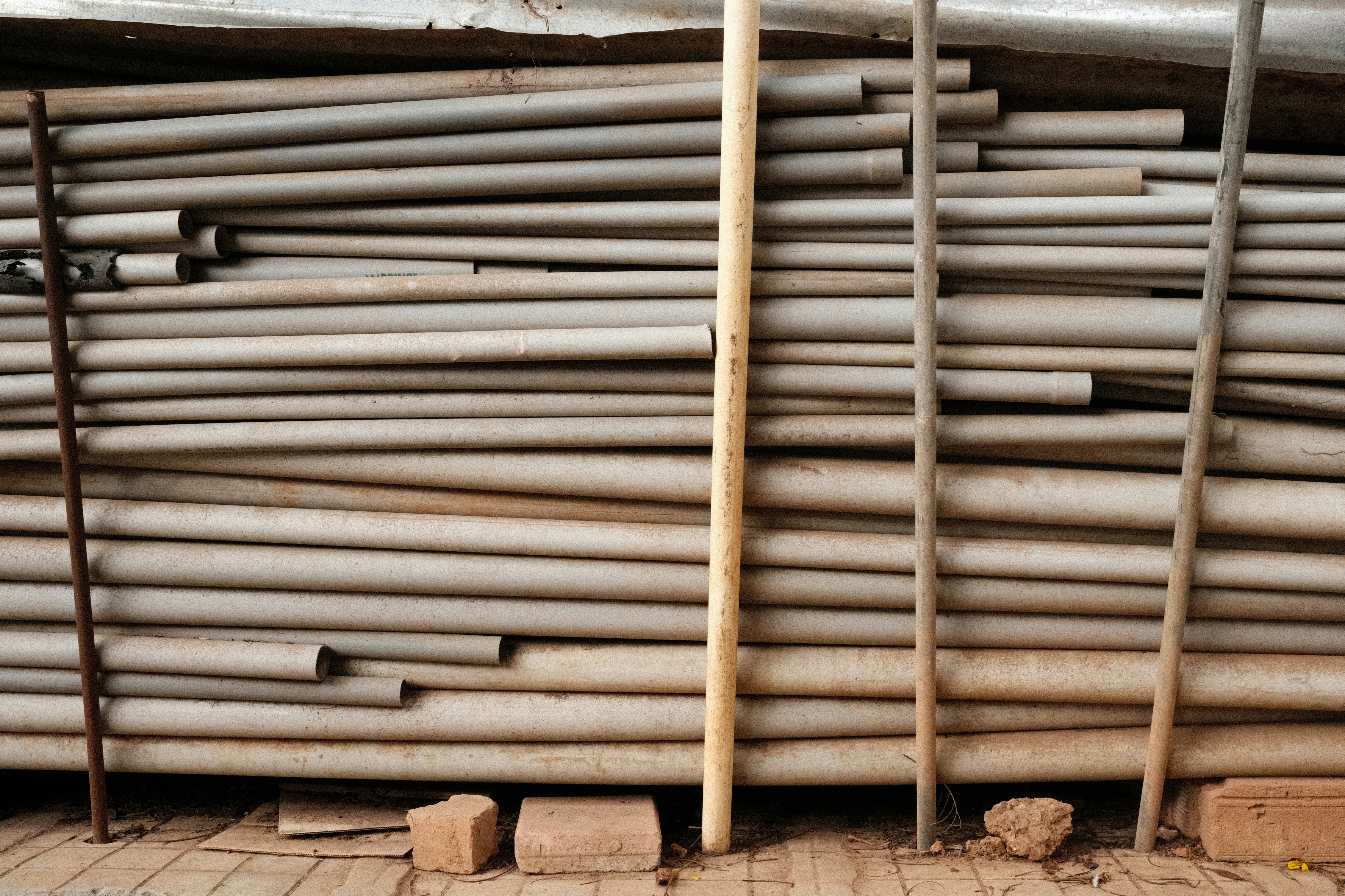 Stack of grey pipes with wooden poles