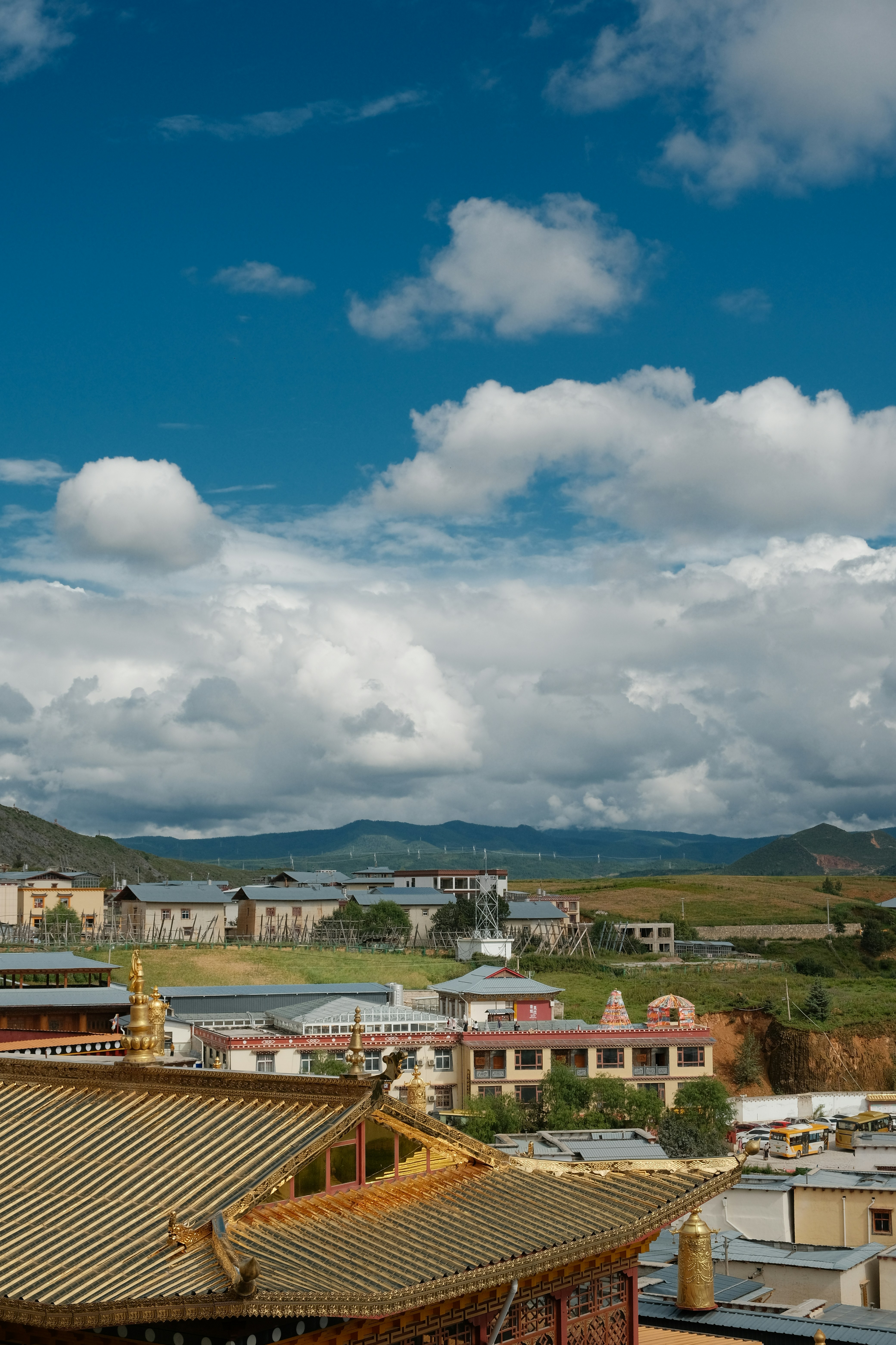Golden temple roofs with distant mountains under clouds.