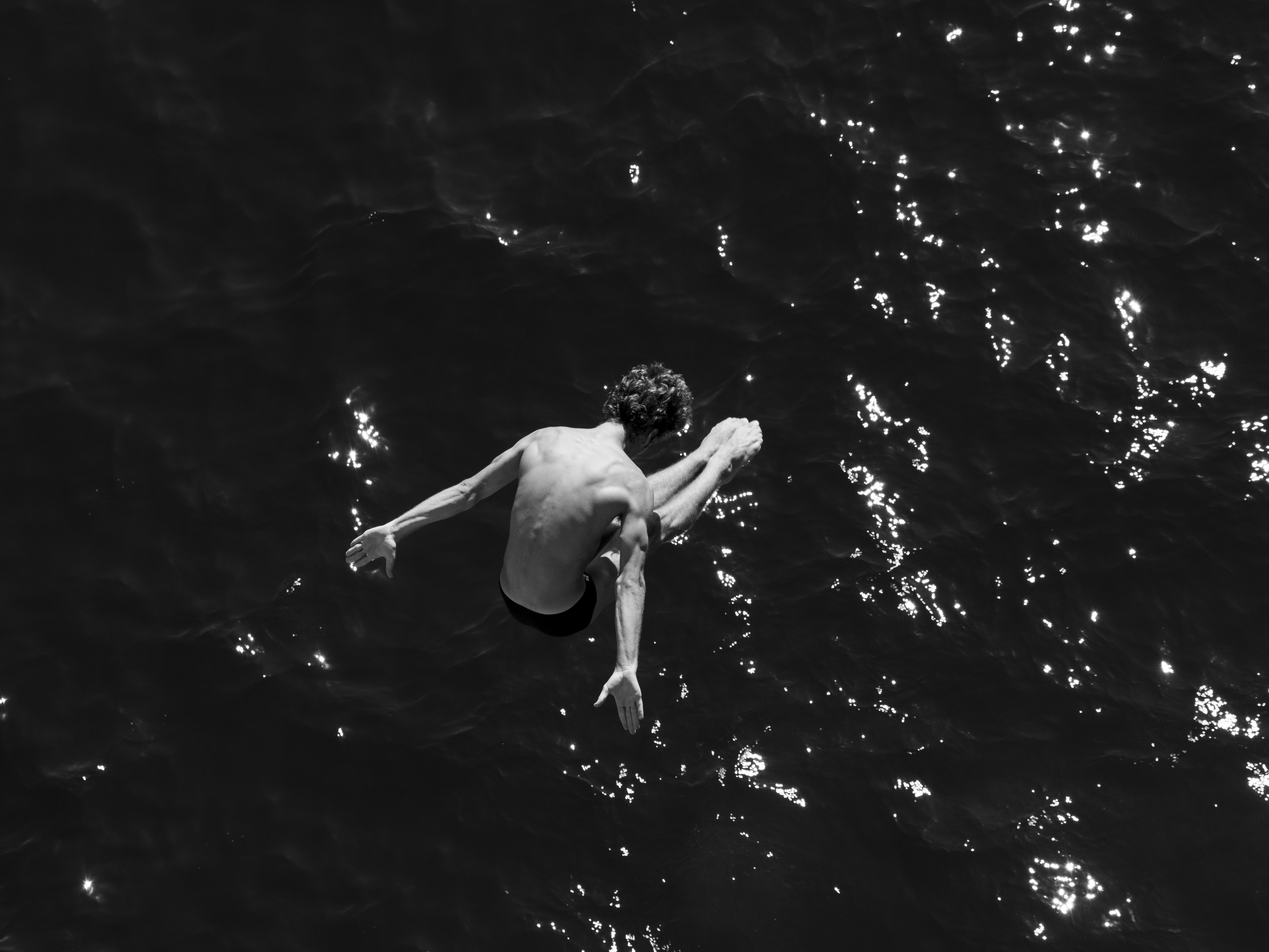 Man diving into dark water from above