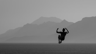 Silhouette of a person jumping against mountains